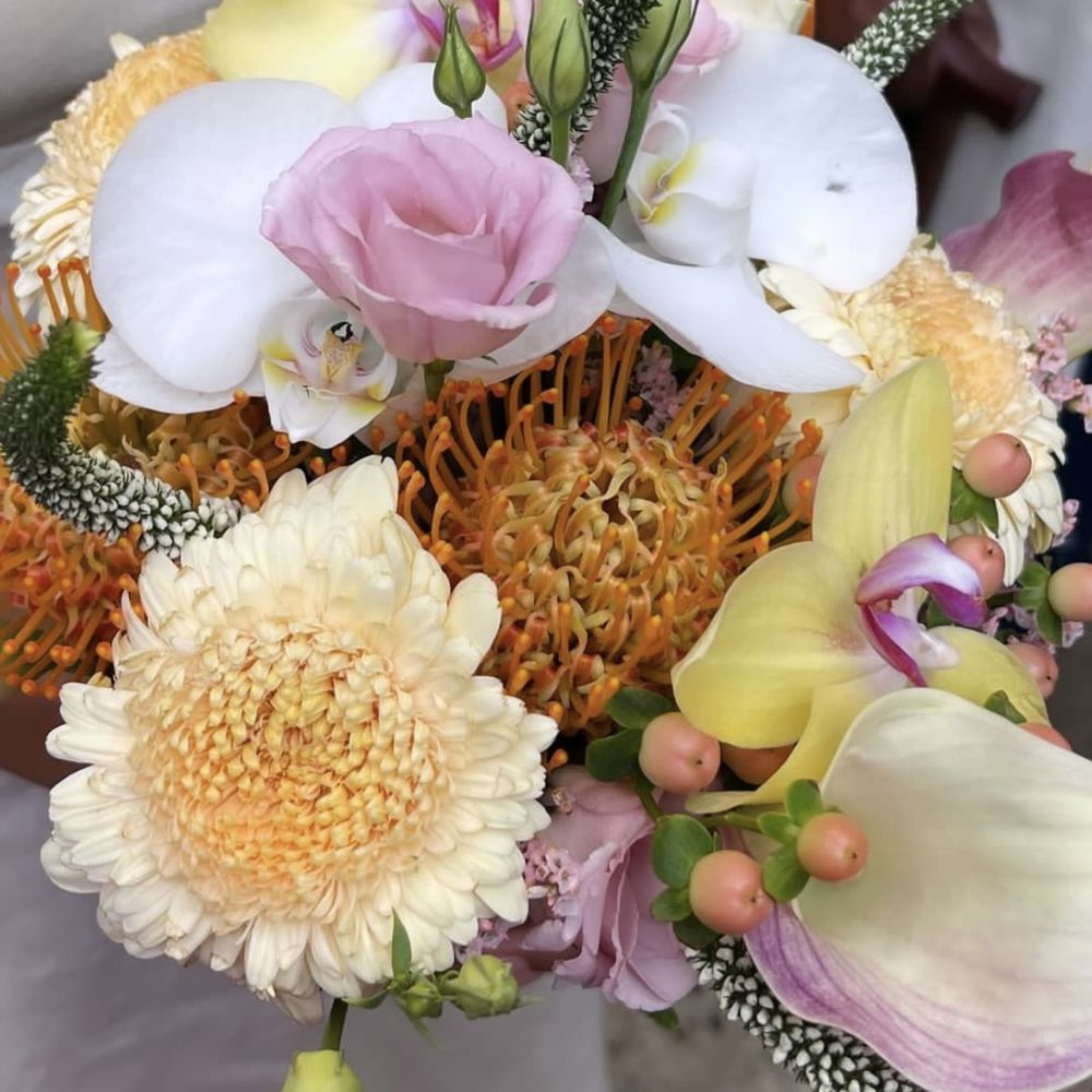 Colorful bouquet with chrysanthemums, proteas, orchids, roses, and berries arranged together