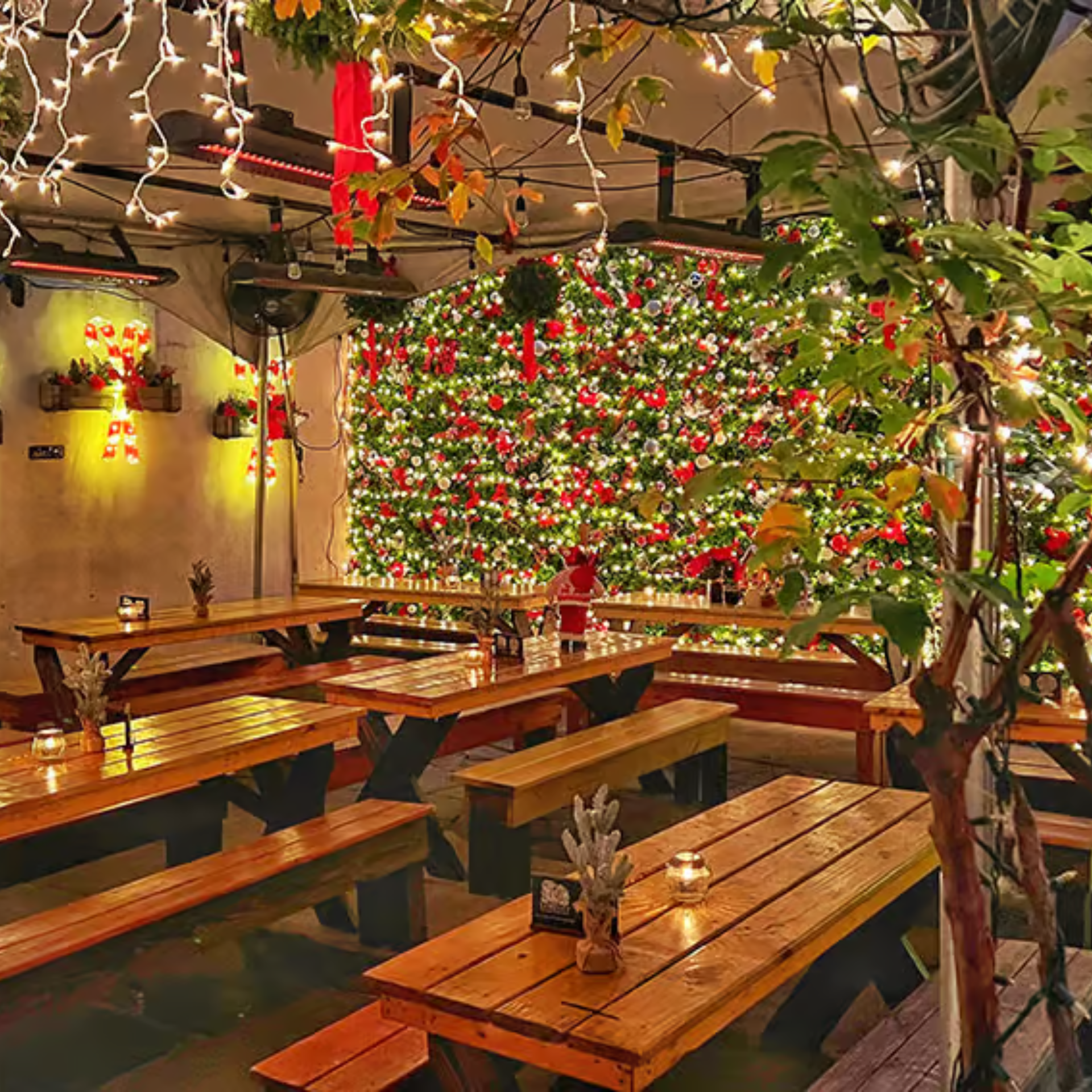 Christmas-themed dining area with wooden tables, twinkling lights, and a wall covered in festive decor