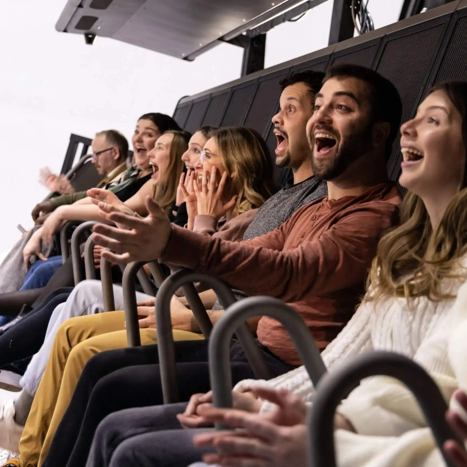 Excited visitors experiencing an immersive ride attraction, reacting with excitement during a motion simulator experience