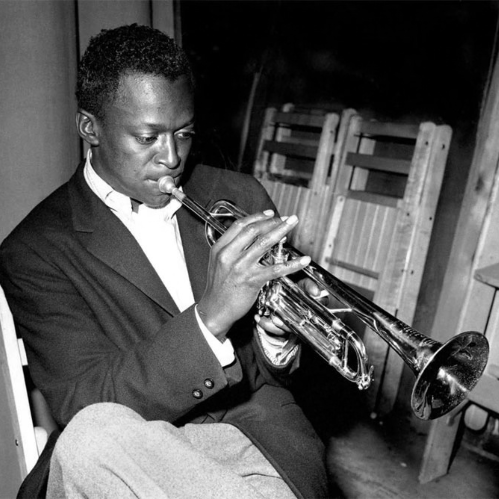 Black-and-white photo of a musician in a suit playing trumpet indoors