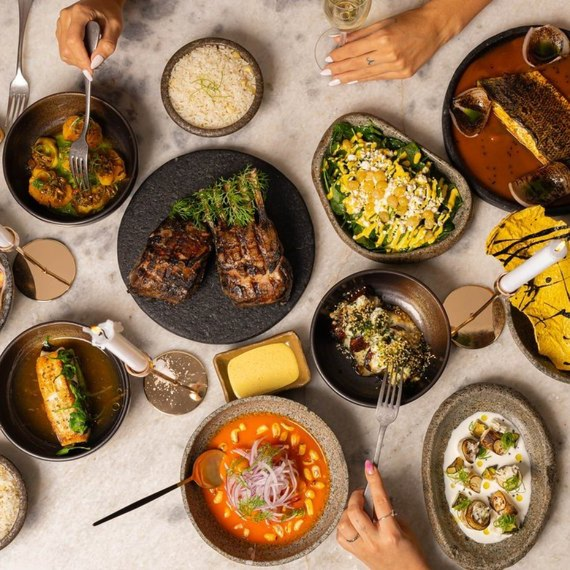 Top-down view of a dining table filled with diverse gourmet dishes, salads, soups, and wine glasses