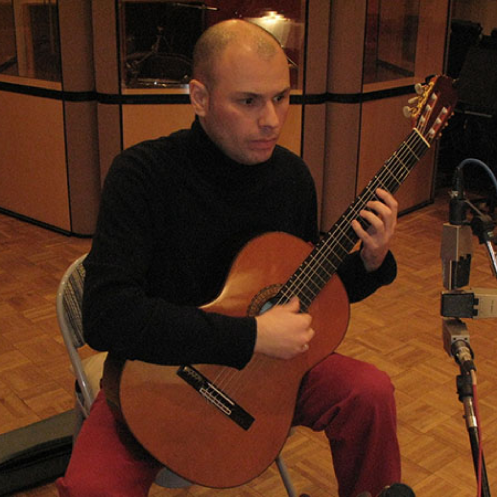Musician in a studio playing classical guitar with microphones set up for recording
