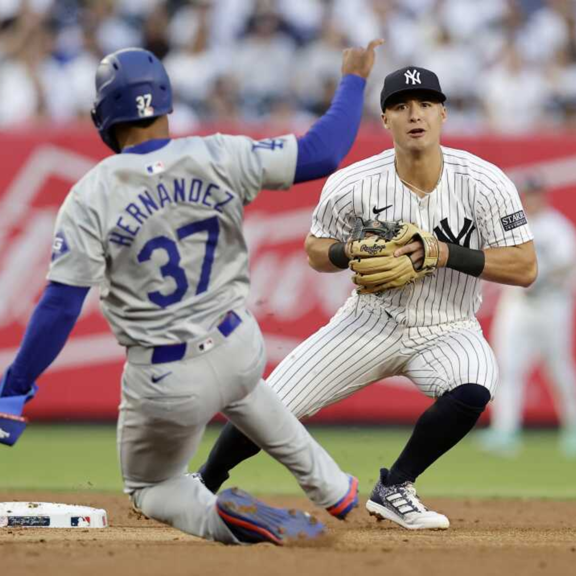 Dodgers player slides toward base as Yankees fielder prepares to tag during MLB game