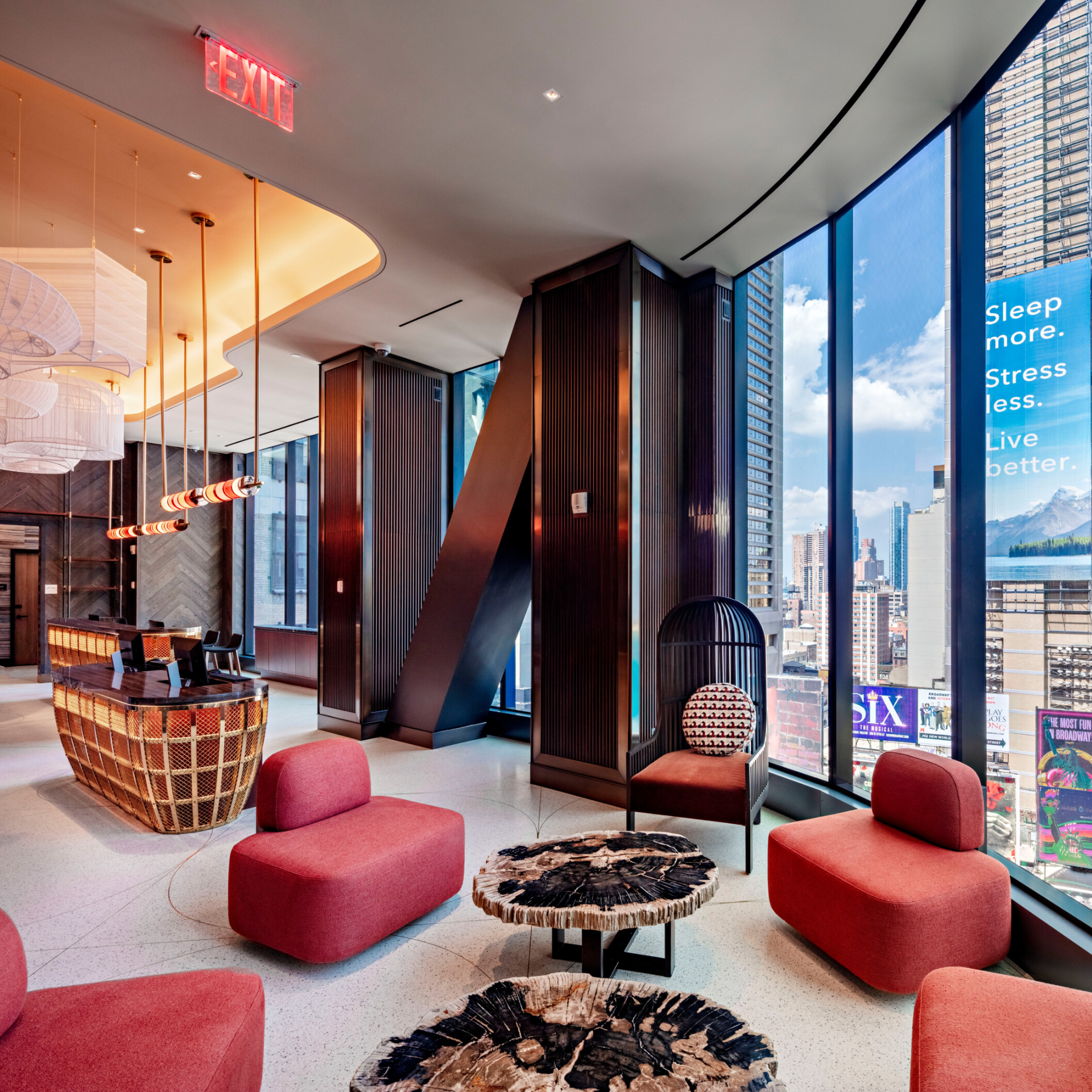 Modern hotel lobby with red chairs, decorative tables, and large windows overlooking a cityscape