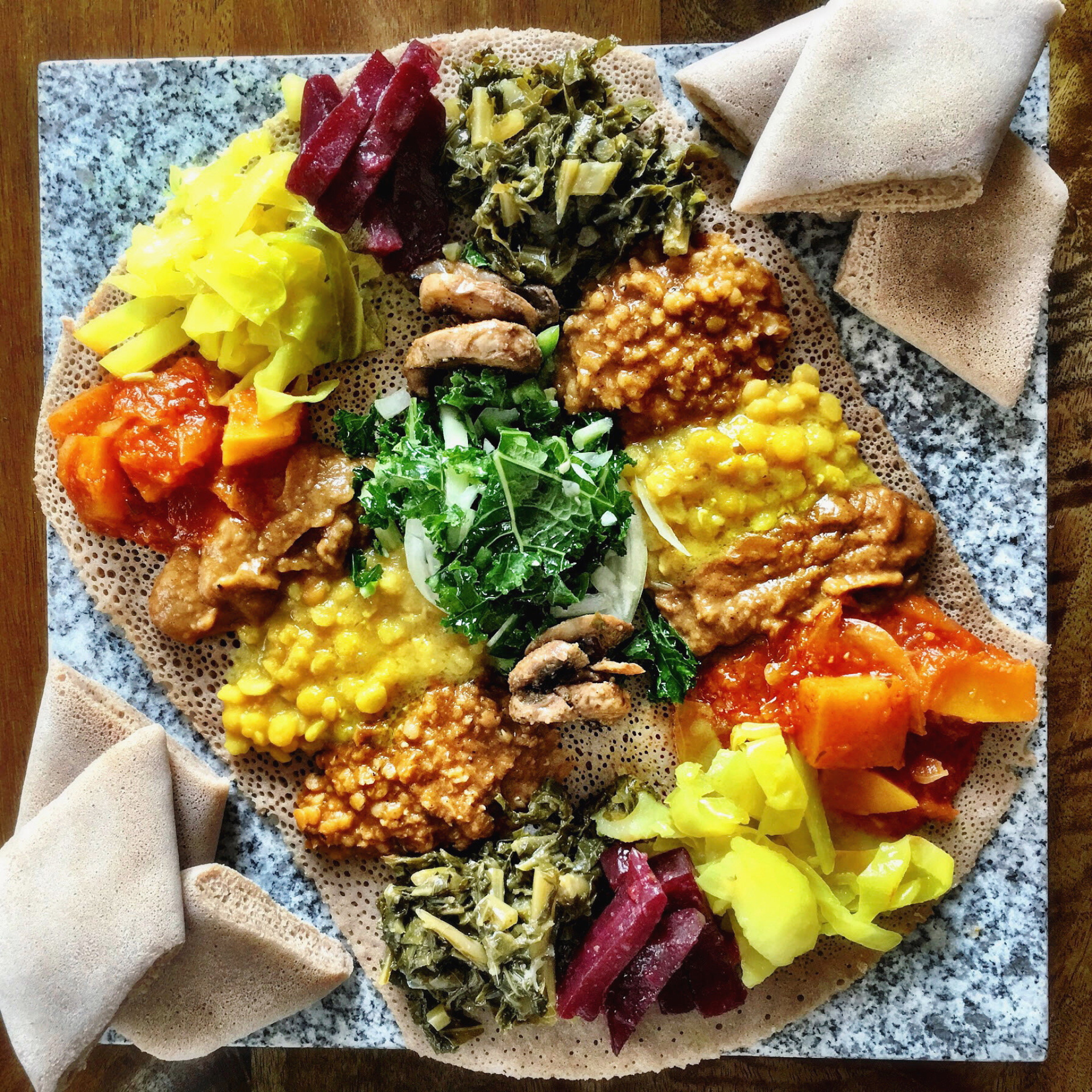 Colorful Ethiopian platter on injera with lentils, greens, and vegetables