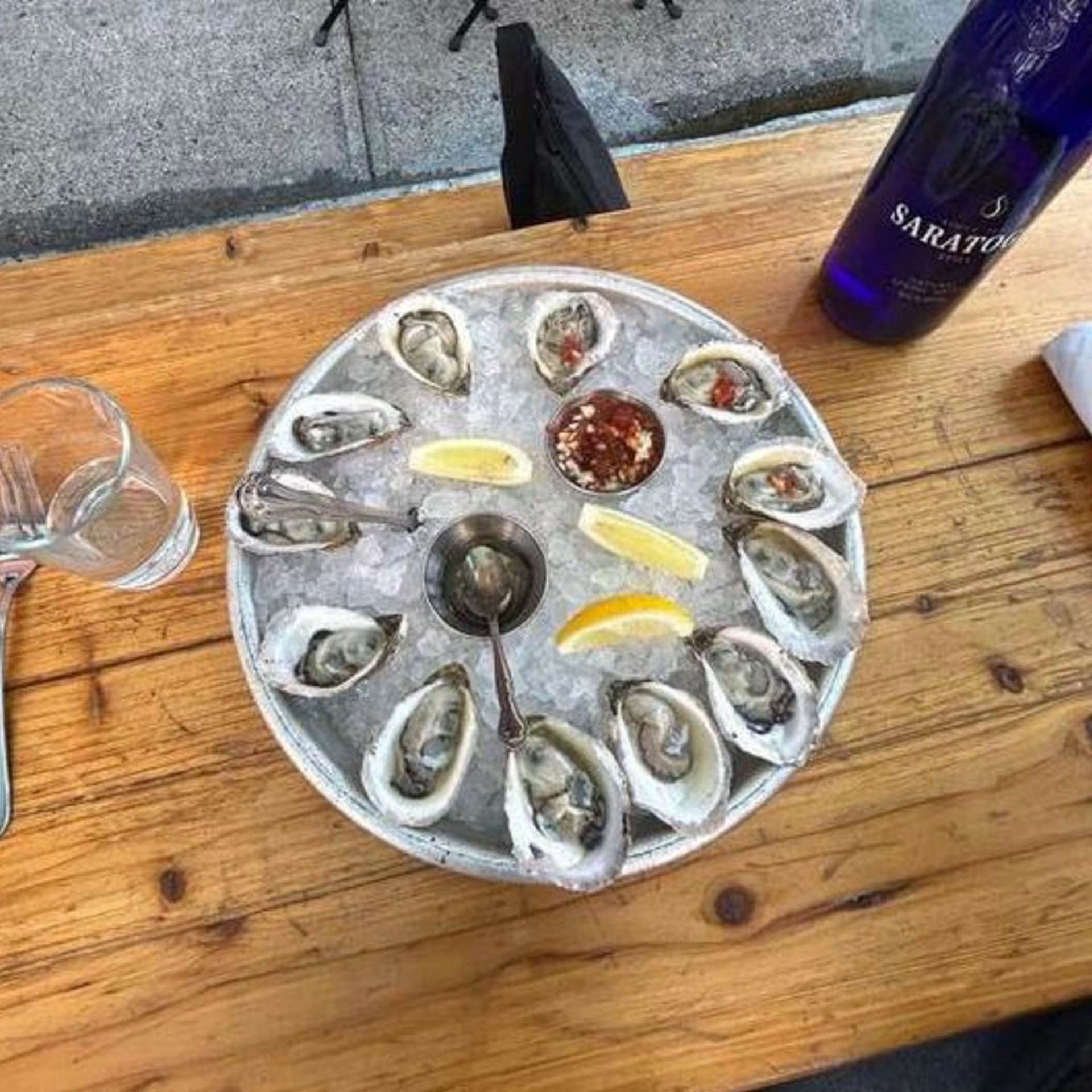 Round tray of oysters on ice with lemon wedges and sauces, casual NYC seafood dining experience featured in daily things to do in NYC any day