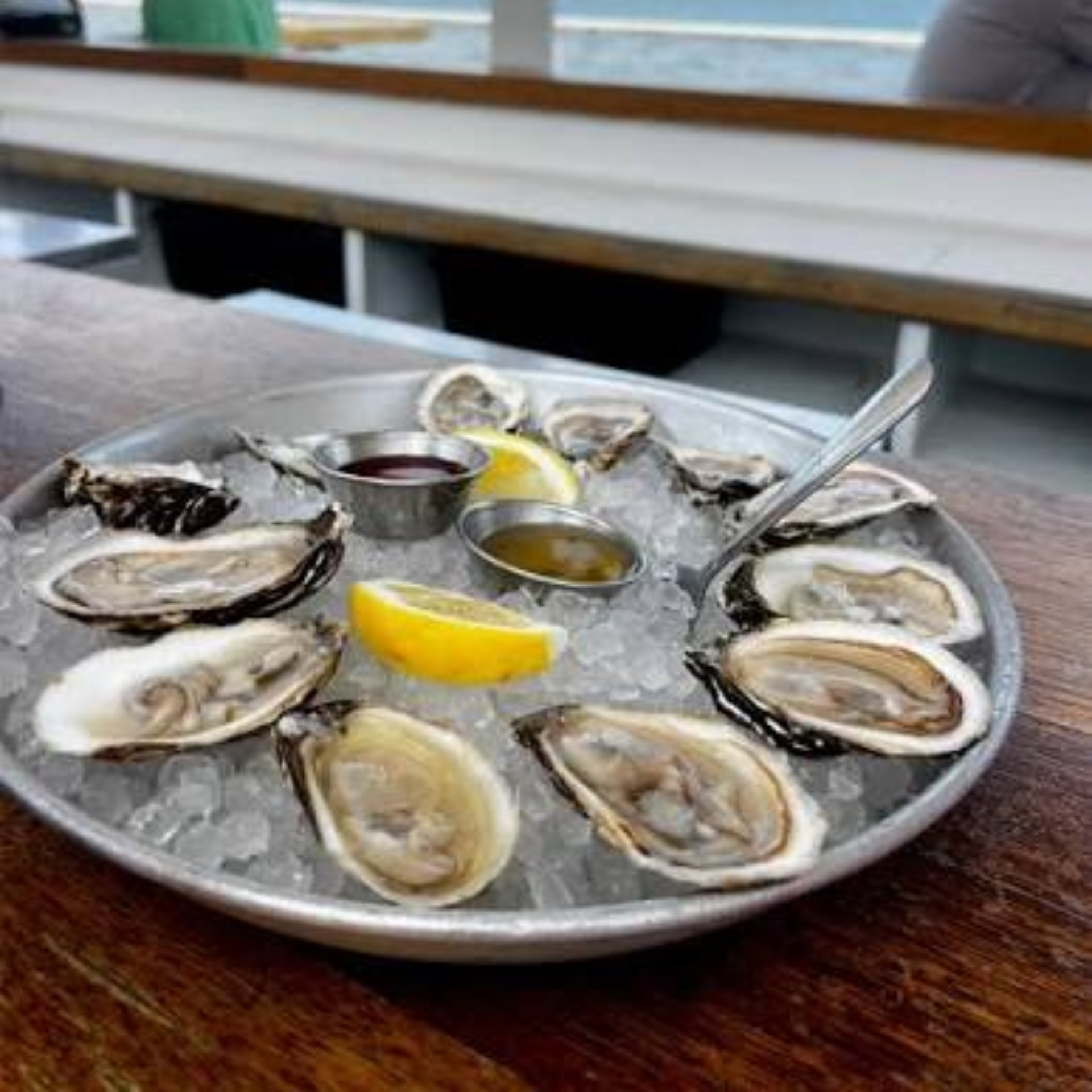 Tray of oysters on ice with lemon wedges and sauces at NYC waterfront dining spot, casual seafood experience featured in daily things to do in NYC any day