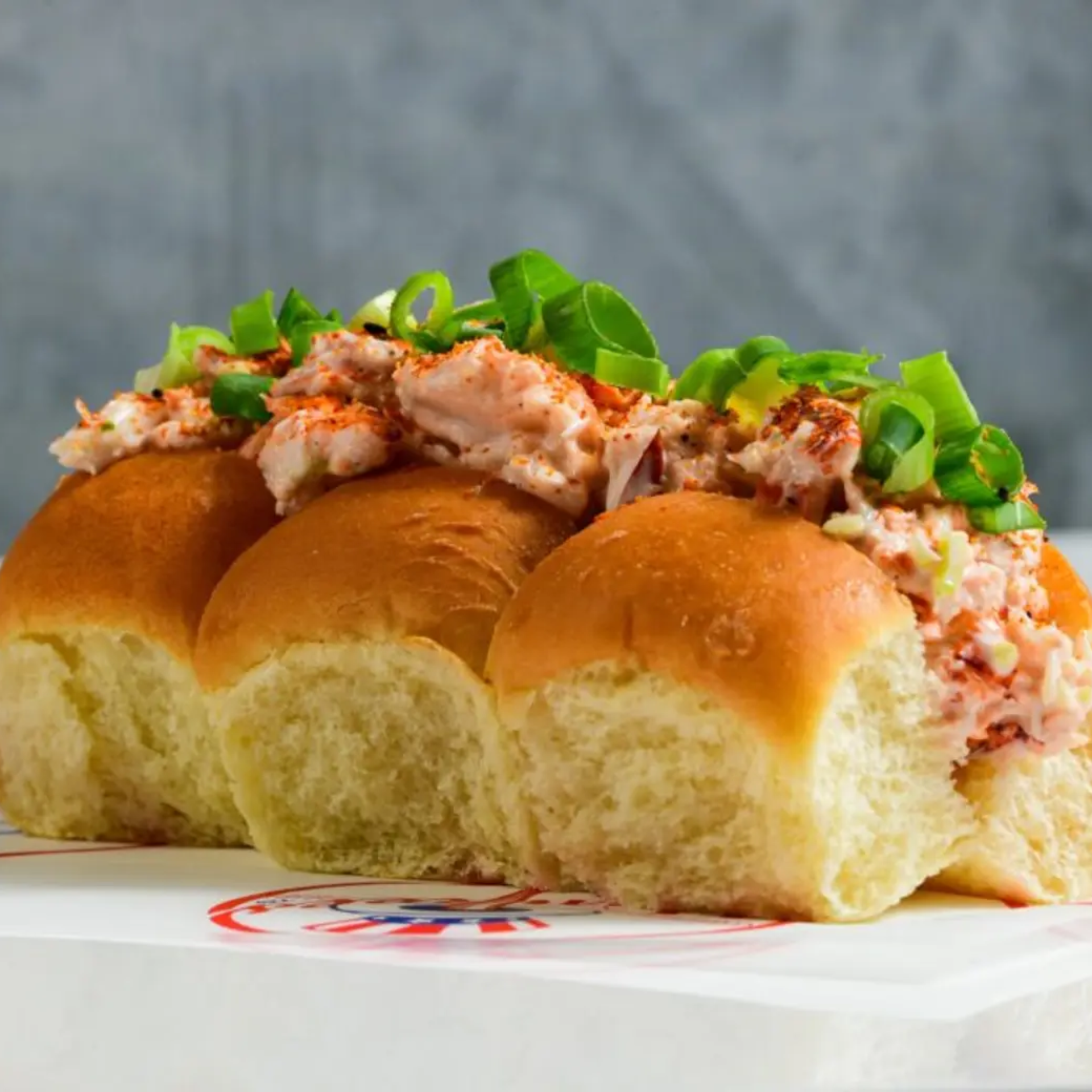 Three bread rolls filled with creamy seafood salad and green onions