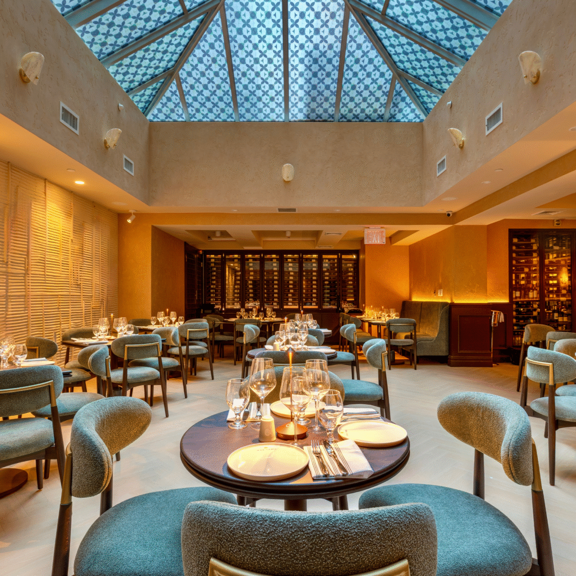 Upscale restaurant with teal chairs, round tables, and a patterned glass ceiling