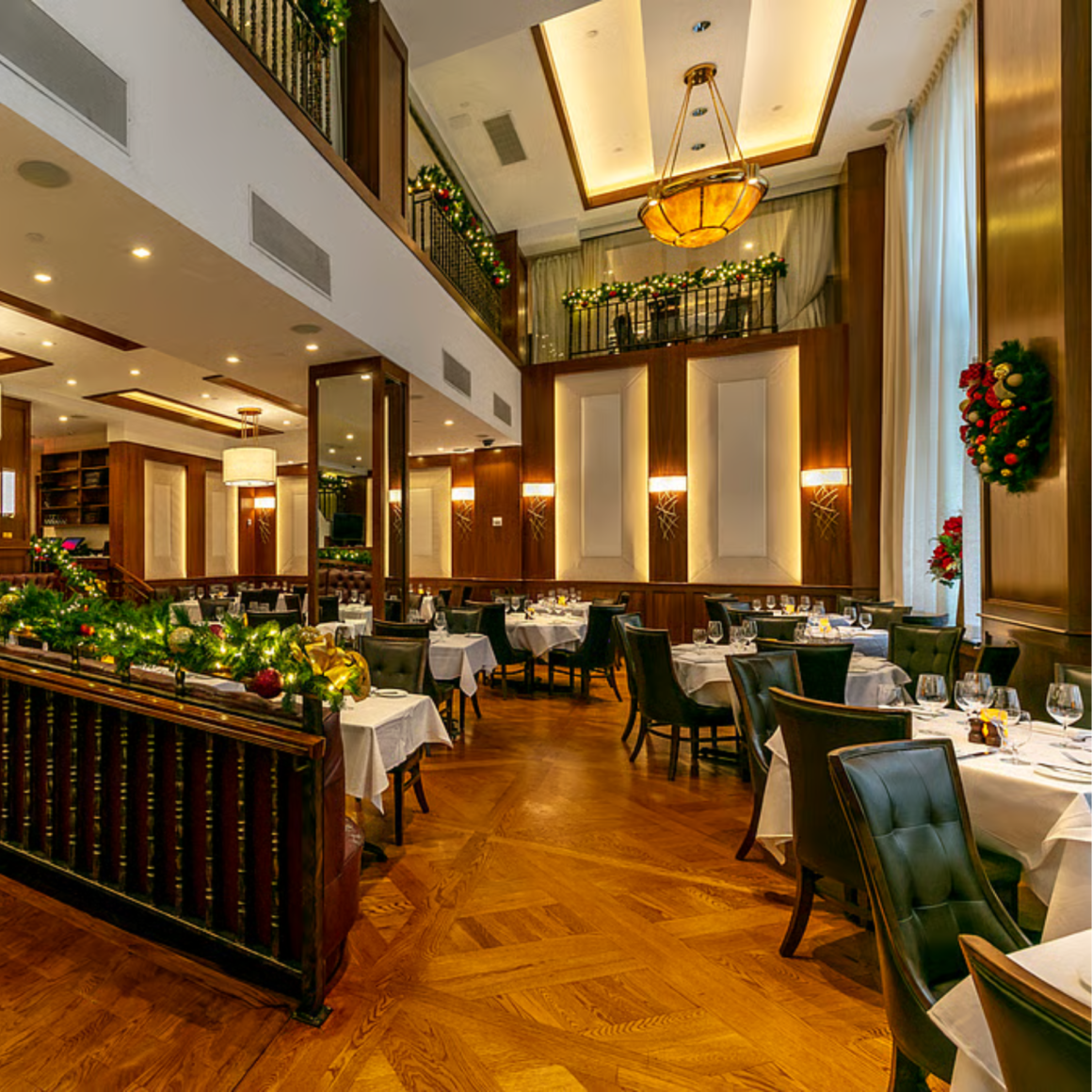 Elegant restaurant interior with festive holiday decorations, white tablecloths, and warm ambient lighting