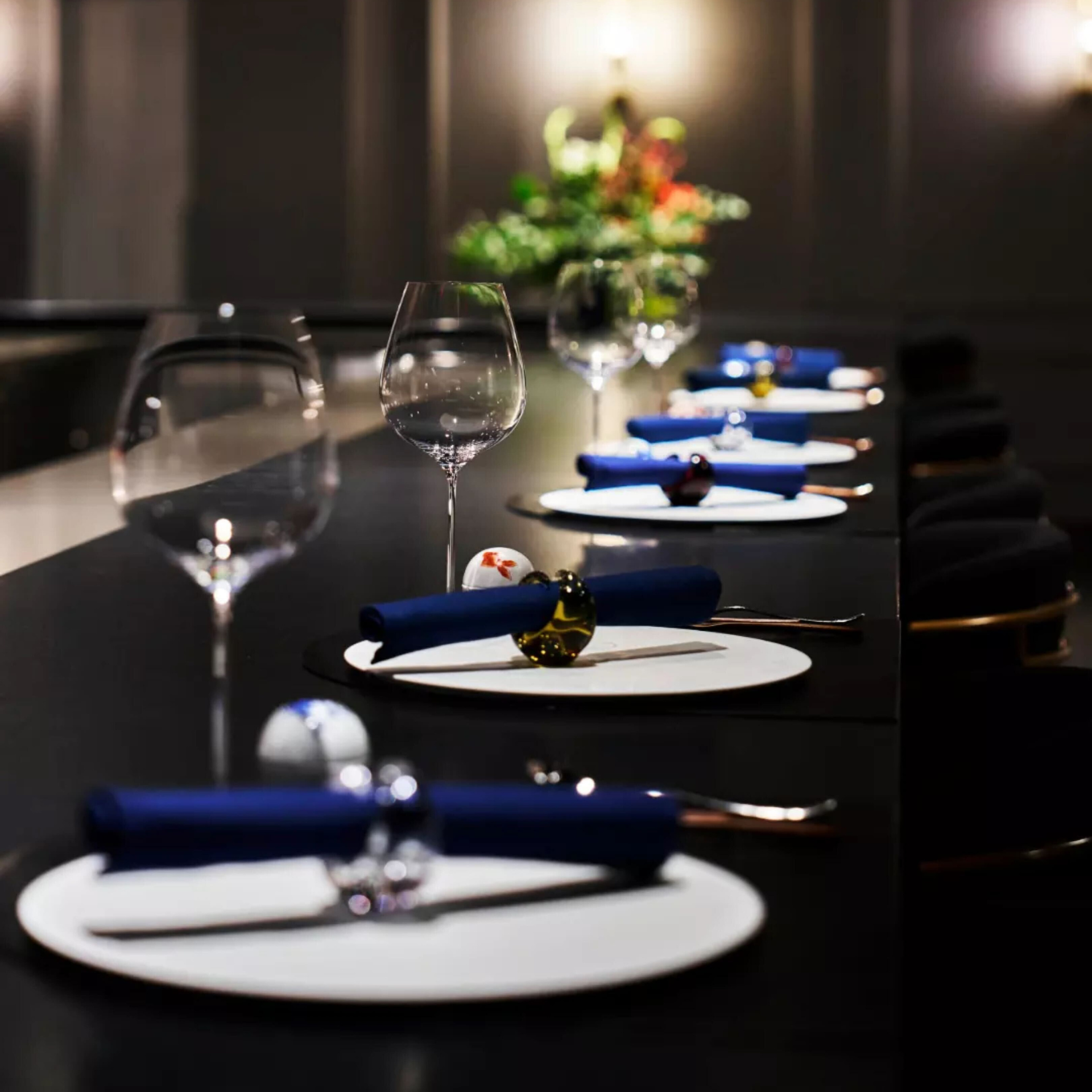 Formal dining table with white plates, blue napkins, wine glasses, and decorative accents