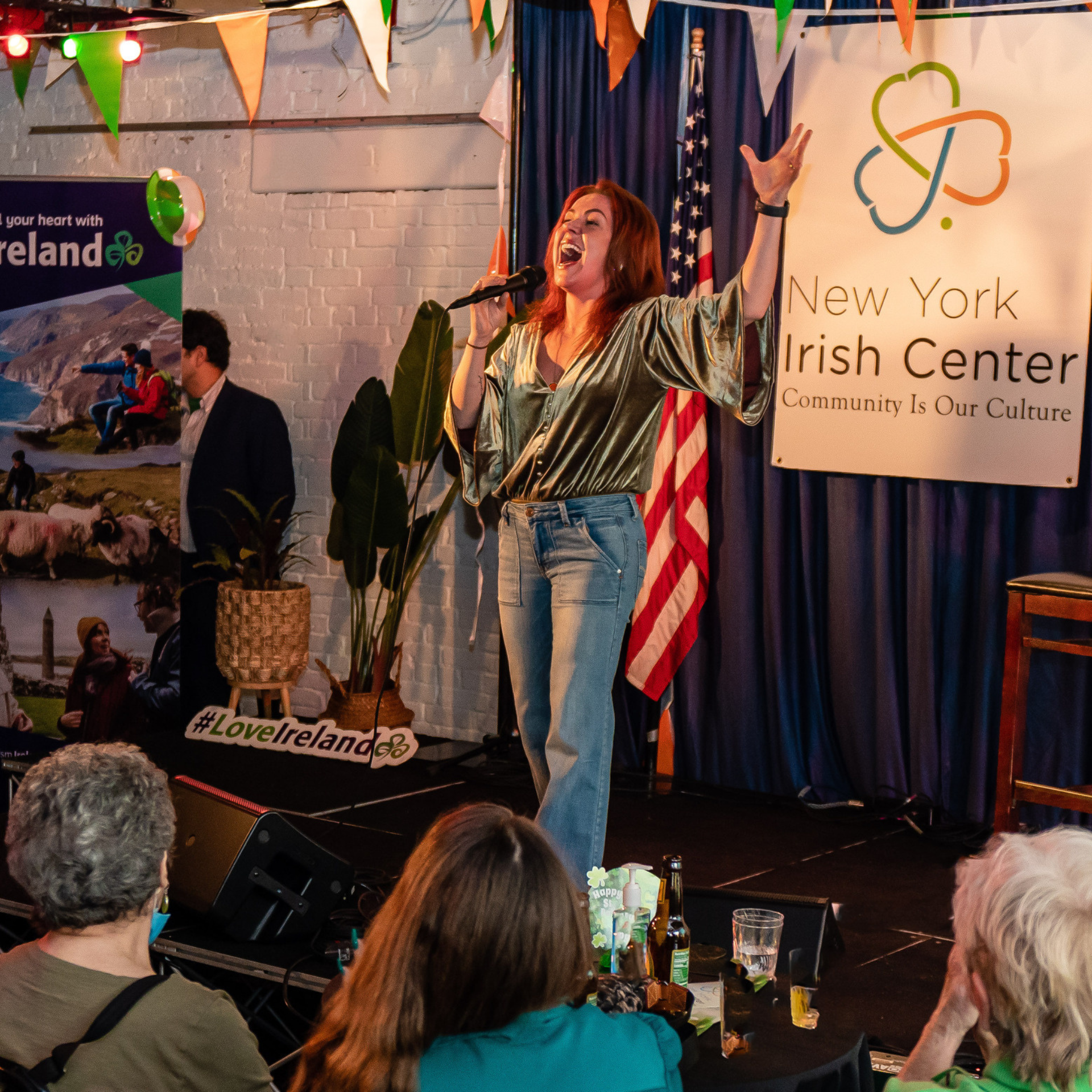 St. Patrick's Day in NYC: Woman performing on stage at New York Irish Center with microphone and festive decorations