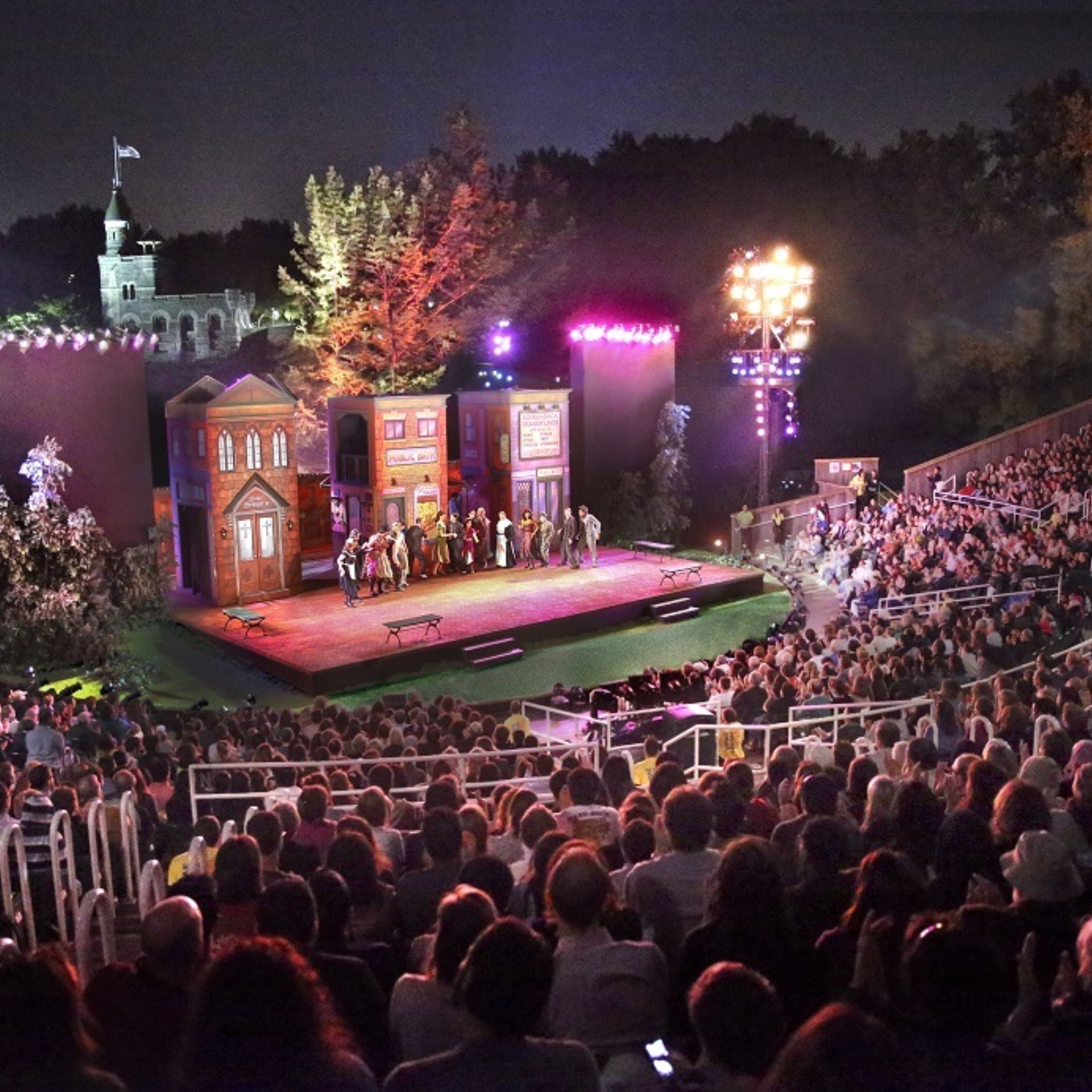Nighttime outdoor theater with elaborate set and large audience