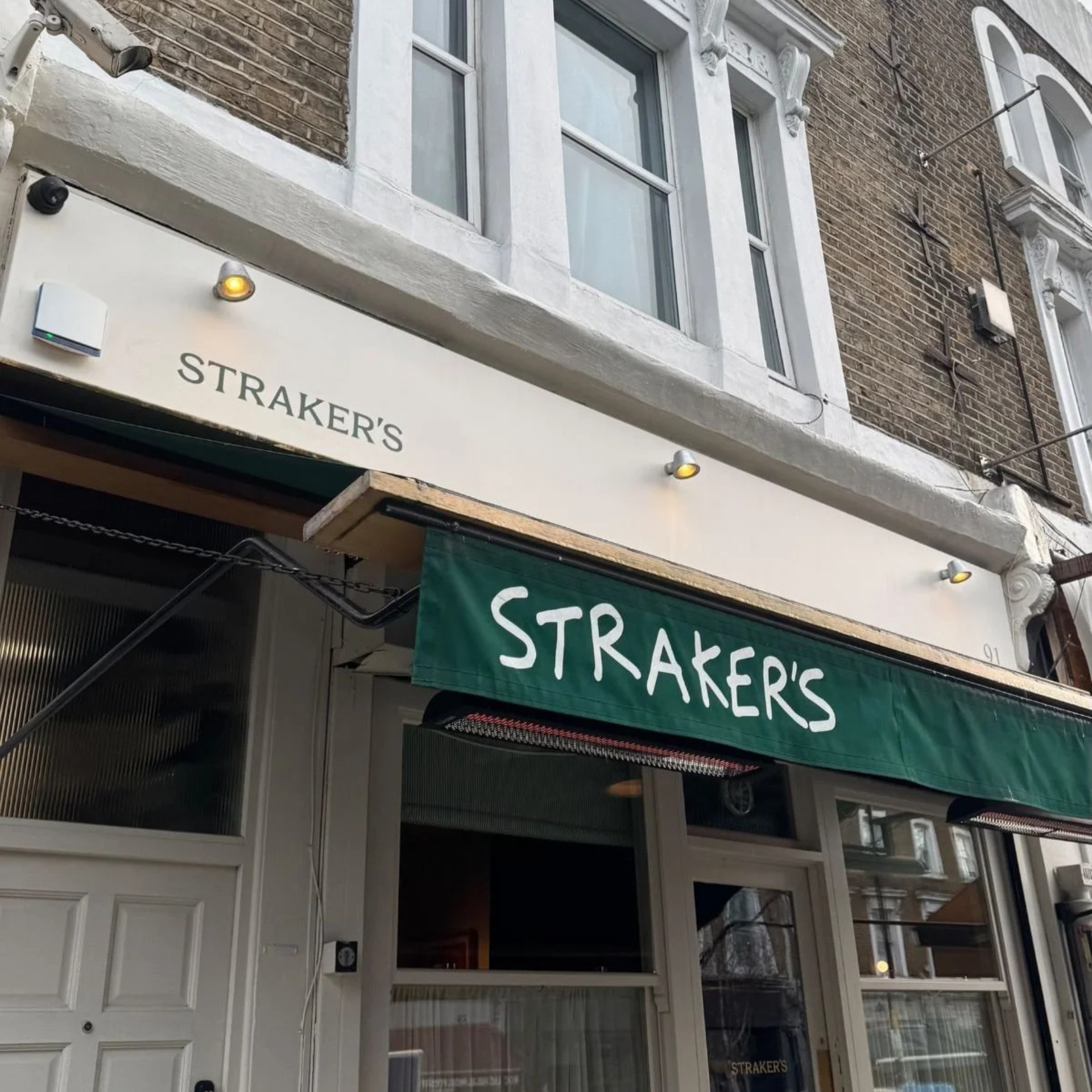 Brick building with Straker’s storefront and green awning