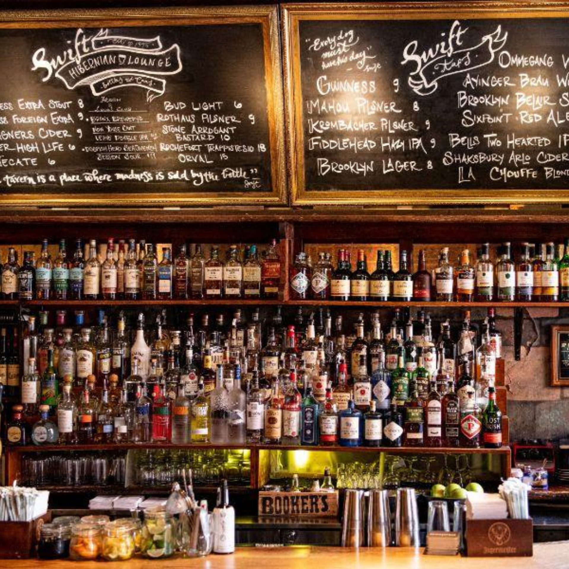 Back bar of Swift Hibernian Lounge with liquor bottles and chalkboards listing beers on tap