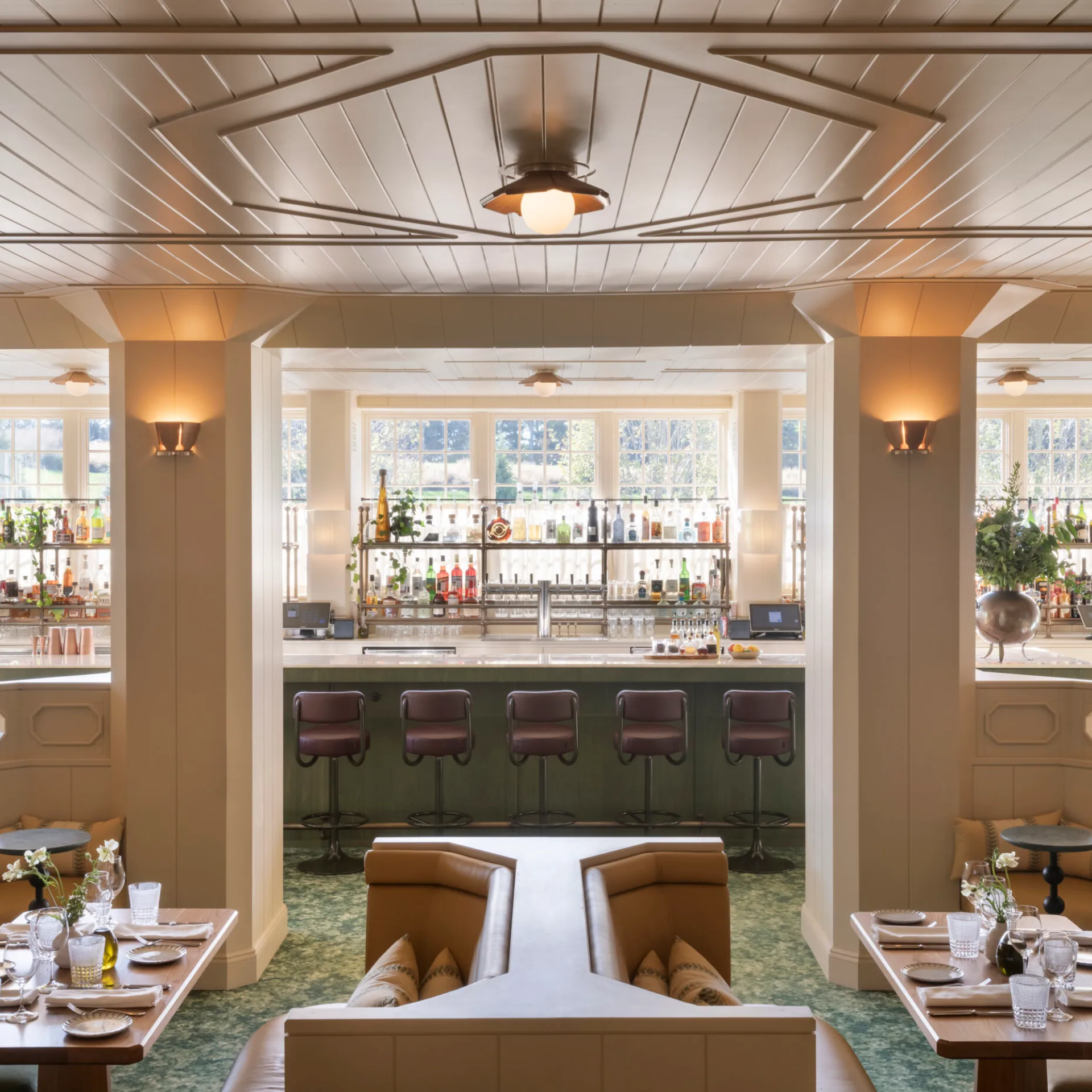 Elegant restaurant interior with marble bar, liquor shelves, leather booths, and modern lighting