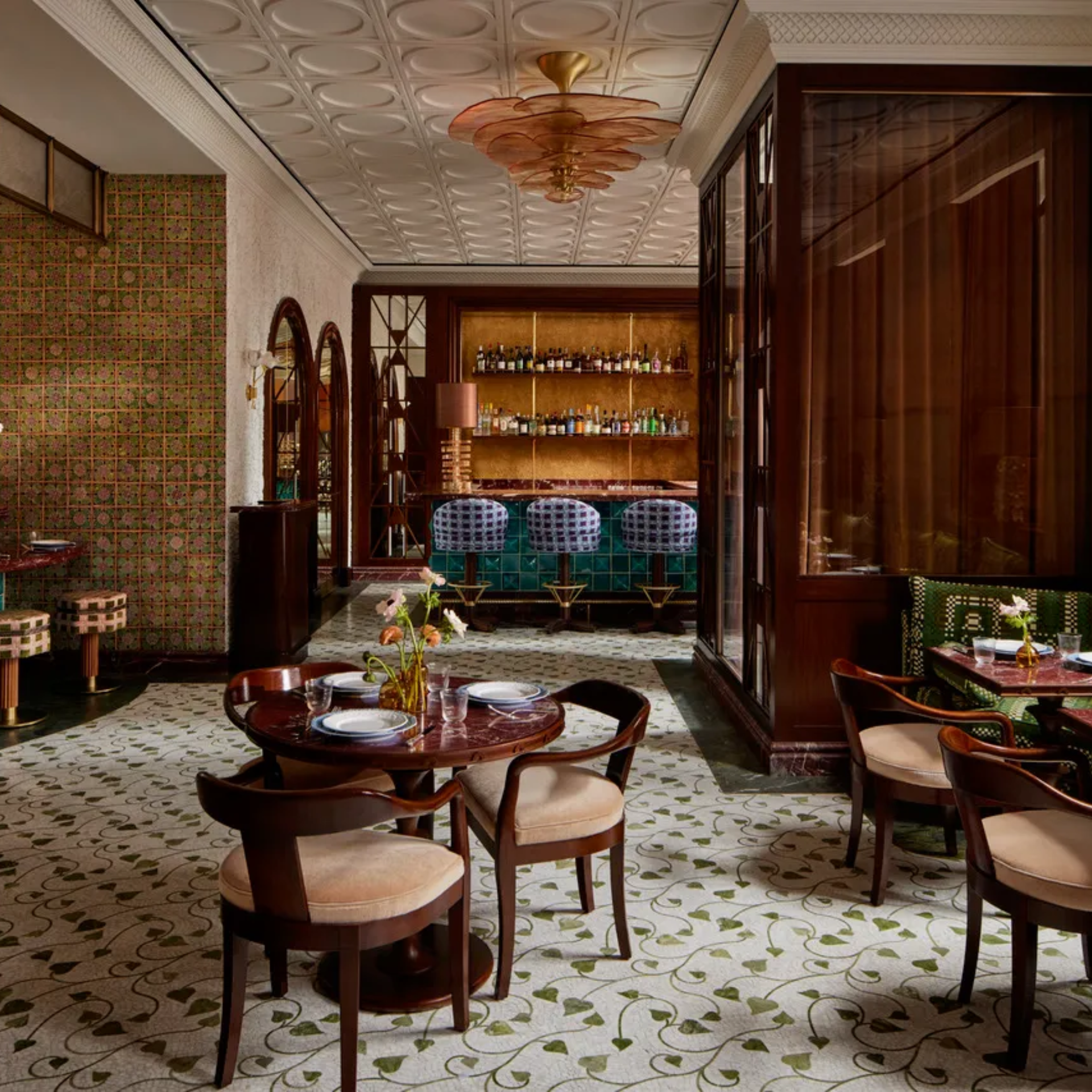 Luxurious restaurant interior with patterned ceiling, chandelier, floral flooring, and bar seating