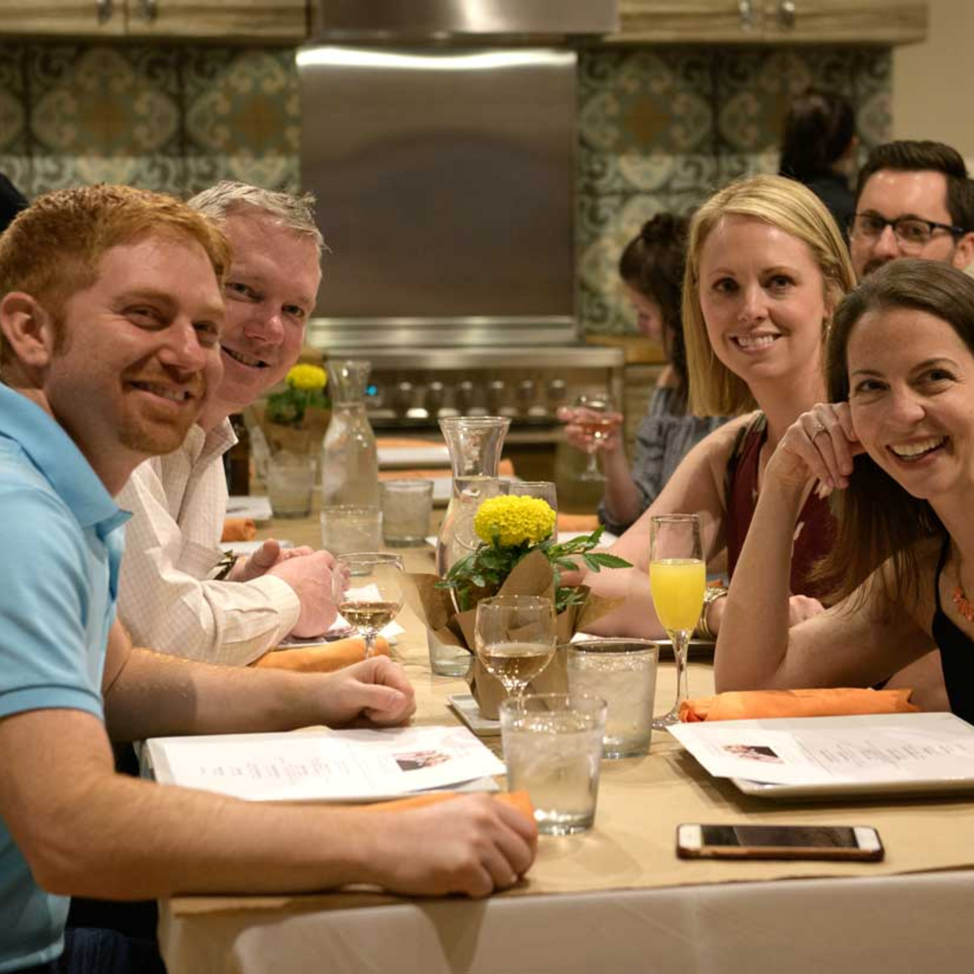 Group dining scene with menus, drinks, and floral centerpieces in cozy modern restaurant setting