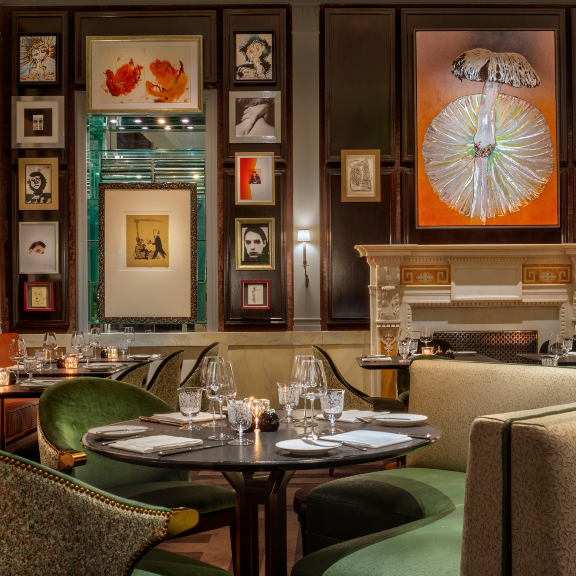Elegant restaurant with green upholstered chairs, round tables, fine art walls, and warm candlelit ambiance