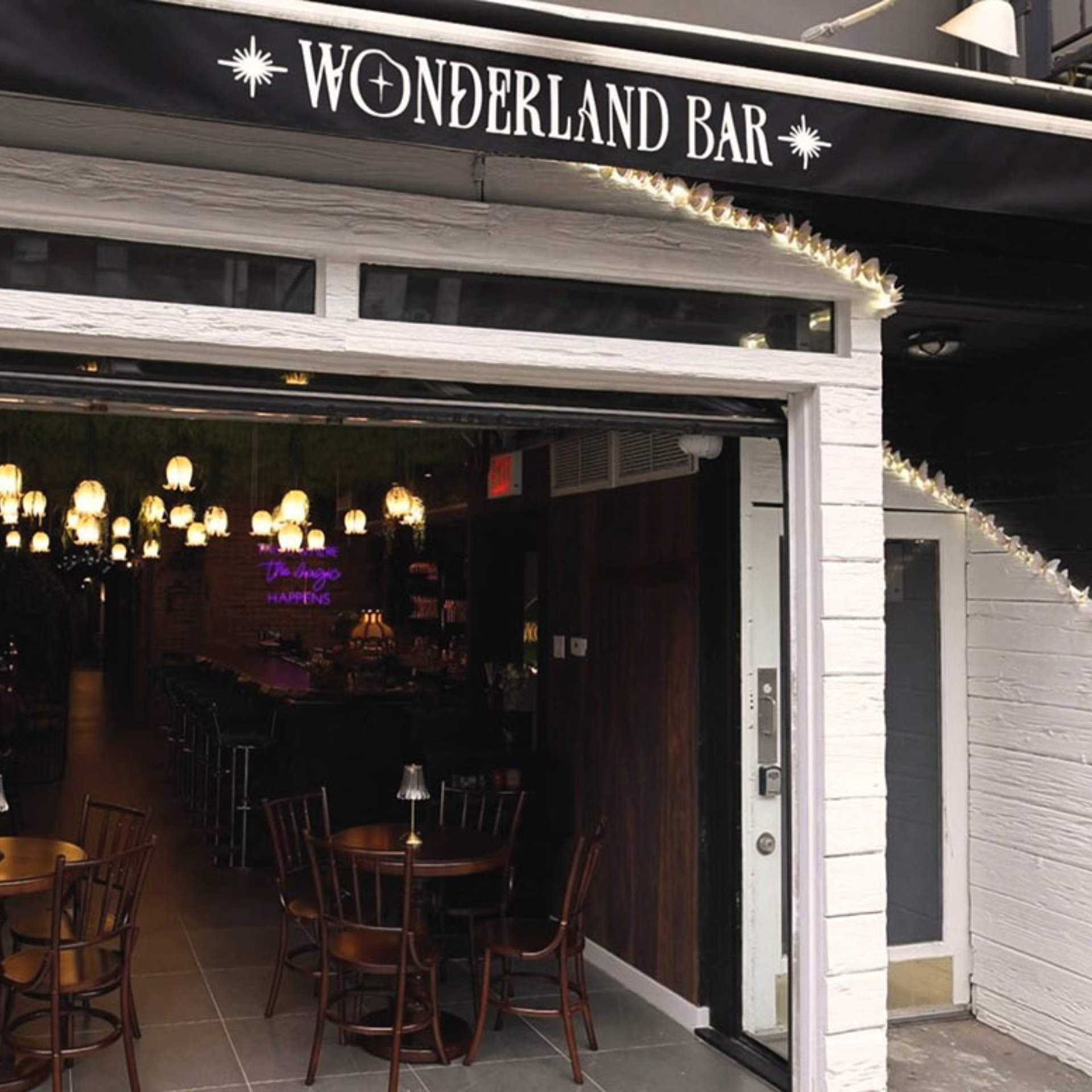 Wonderland Bar entrance with stylized sign, cozy interior of flower‑shaped lights, wooden tables, bar counter, and neon sign reading ‘The magic happens