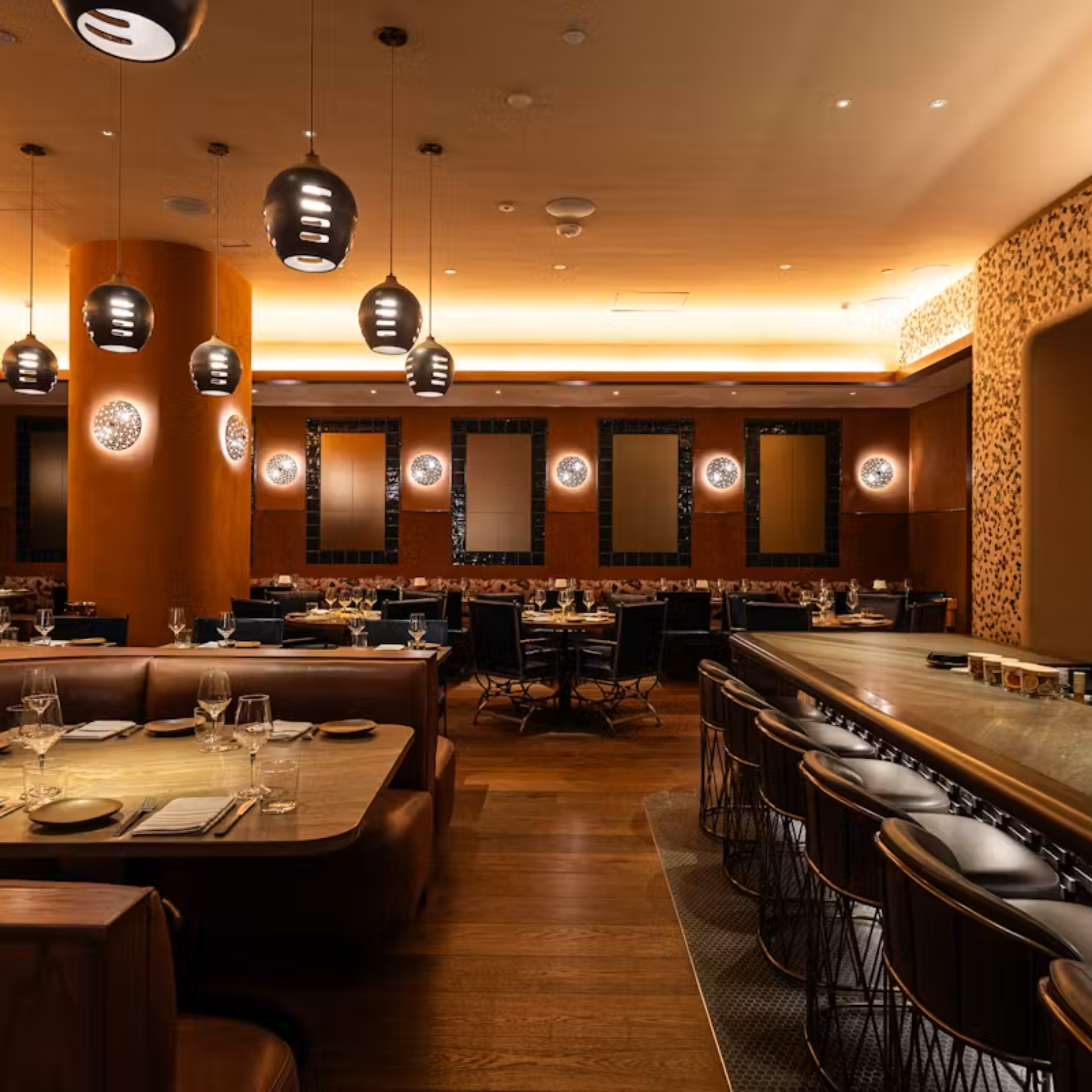 Upscale NYC restaurant interior with warm pendant lighting, booth seating, and bar counter, sophisticated dining spot for food lovers, nightlife, and daily things to do in NYC any day