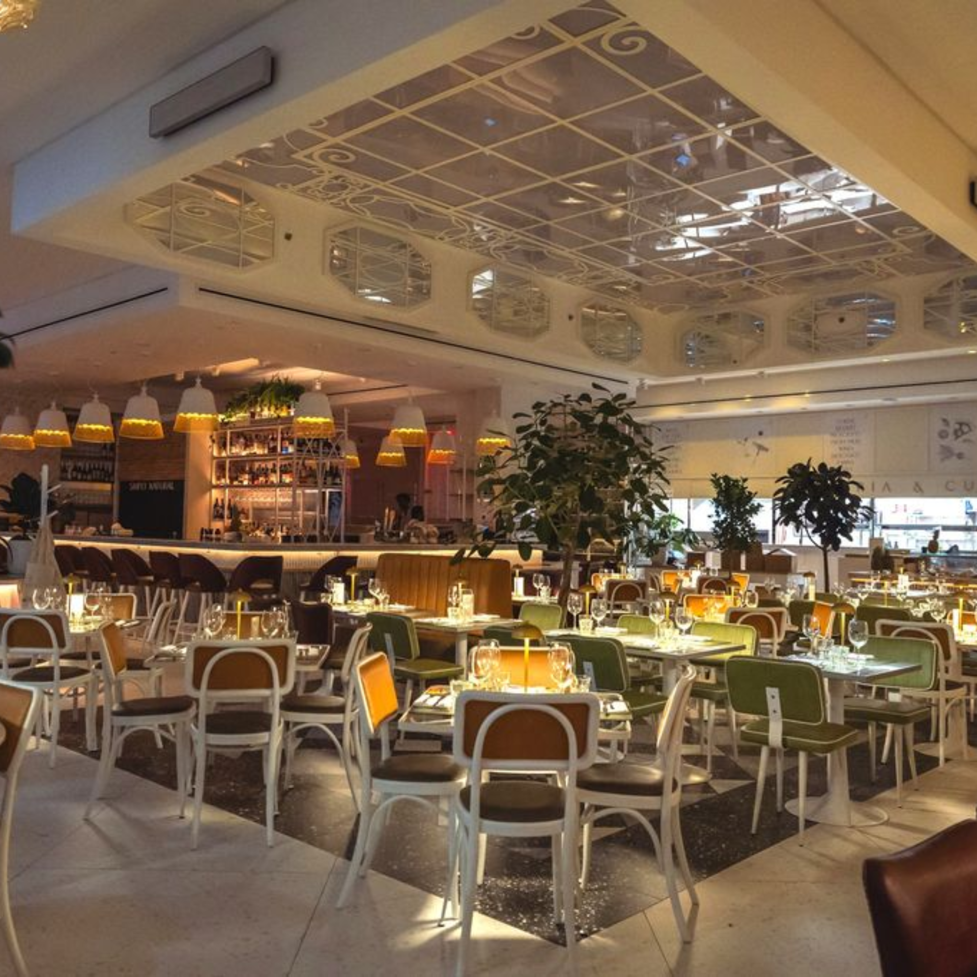 Contemporary NYC restaurant interior with green chairs, pendant lamps, mirrored ceiling, and bar area, inviting dining spot for food lovers, nightlife, and daily things to do in NYC any day