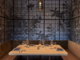 Cozy restaurant booth with wooden table, cushioned seating, warm pendant light, and artistic wall of circular patterns and shadows