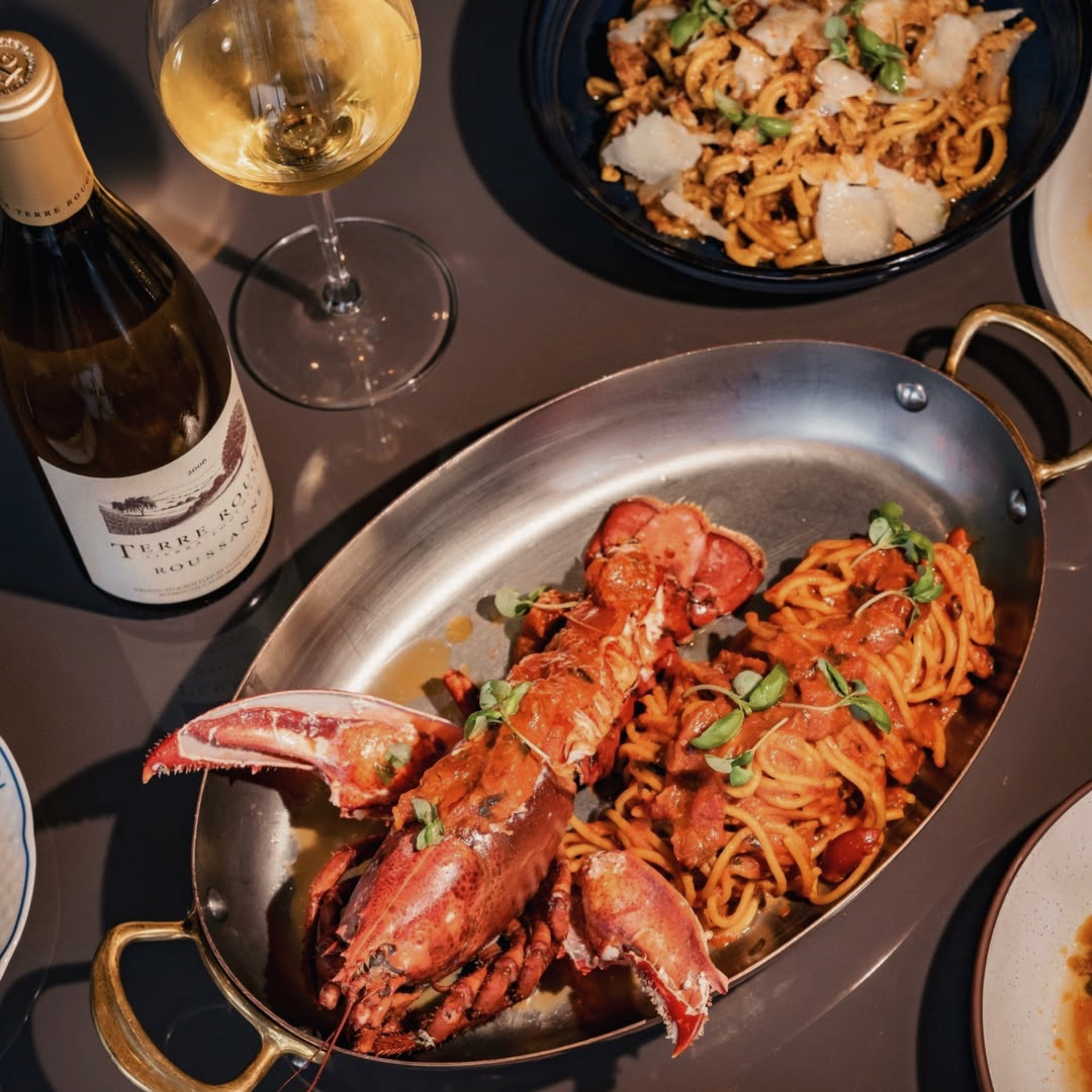 Lobster with pasta in red sauce, served with wine