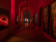 NYC art exhibition hallway with red lighting, abstract fiery artworks on walls, spotlights, and dramatic immersive atmosphere, cultural gallery experience featured in daily things to do in NYC any day