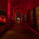 NYC art exhibition hallway with red lighting, abstract fiery artworks on walls, spotlights, and dramatic immersive atmosphere, cultural gallery experience featured in daily things to do in NYC any day