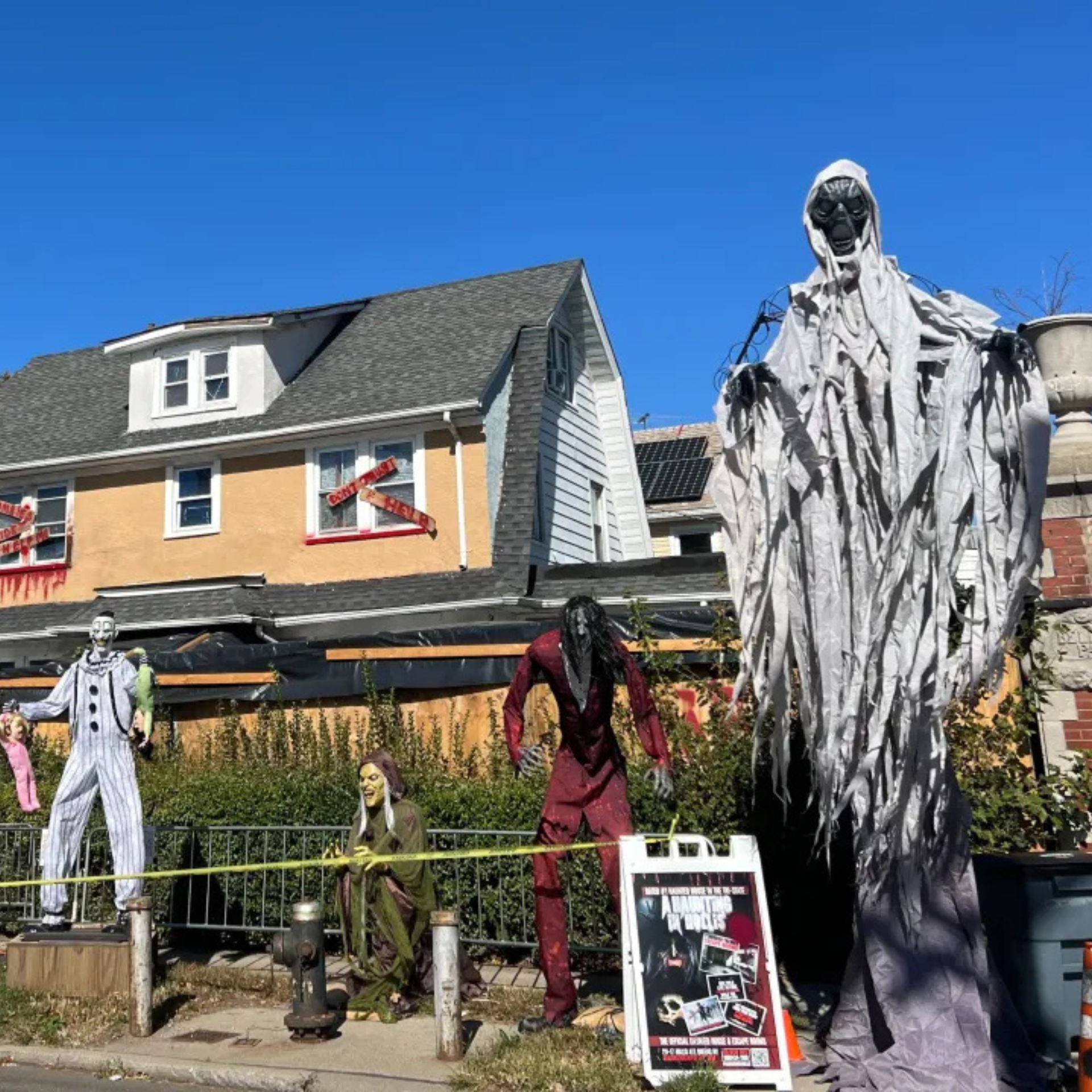 House decorated with Halloween figures: ghost, clown, zombie, and spooky props in the yard and windows