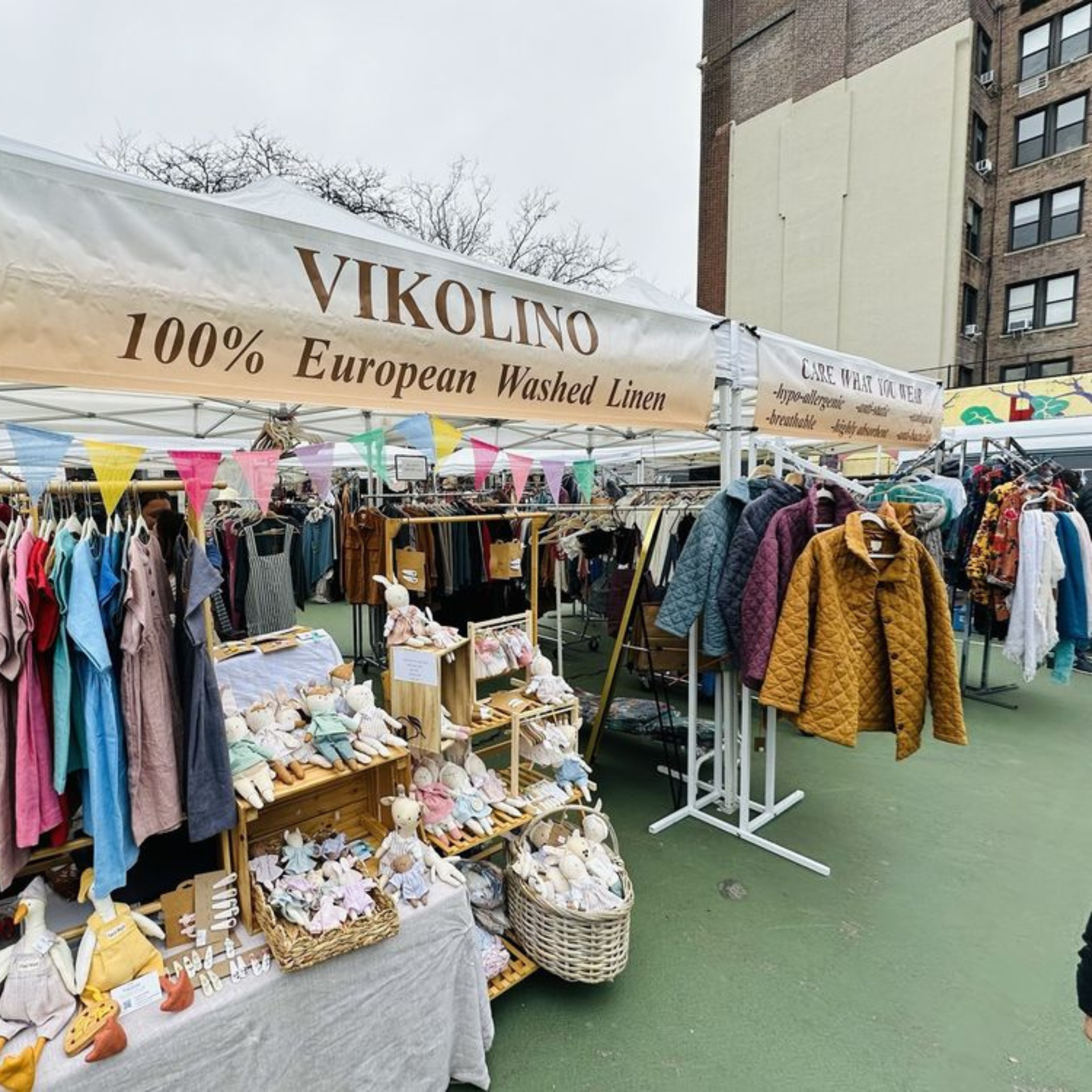 Outdoor market with linen and wellness apparel stalls under white tents