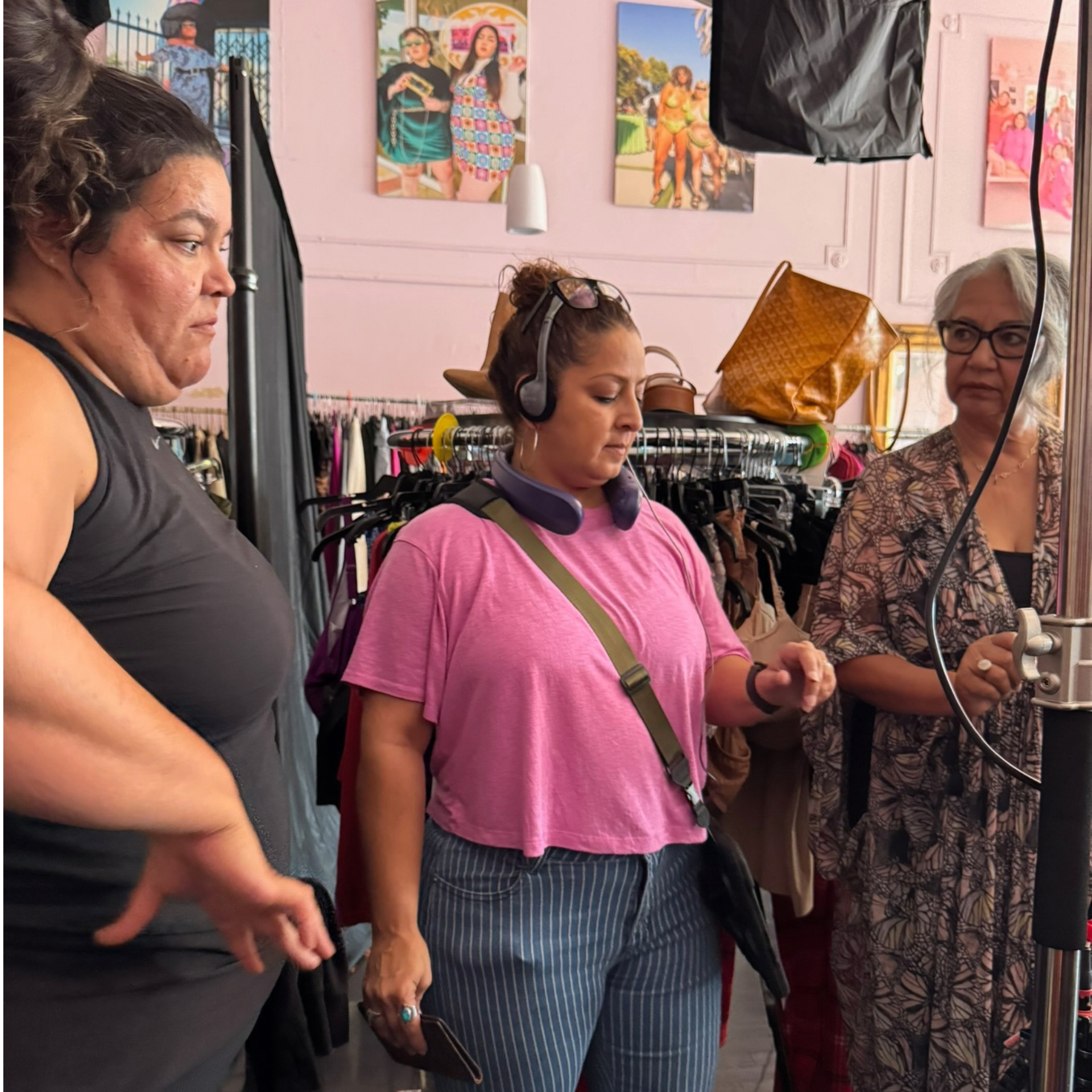 Three people in clothing store with racks and fashion posters