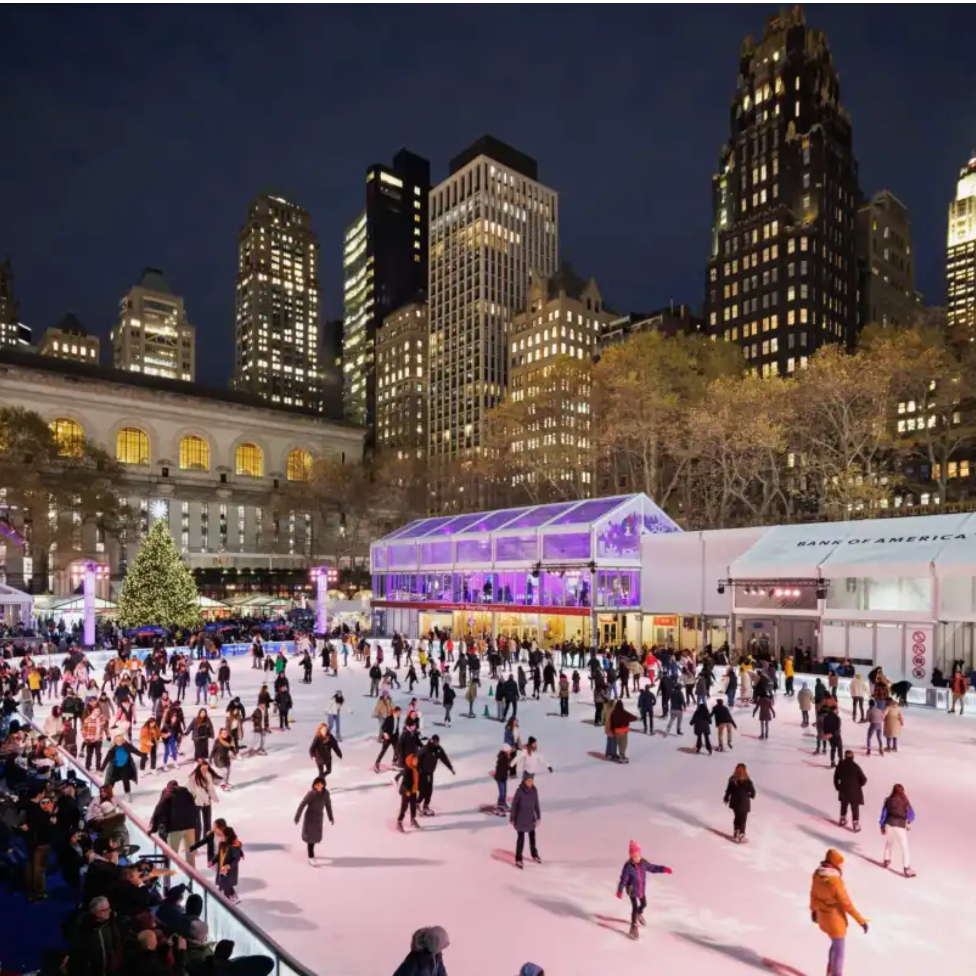 Crowded city ice rink at night with Christmas tree and skyscrapers