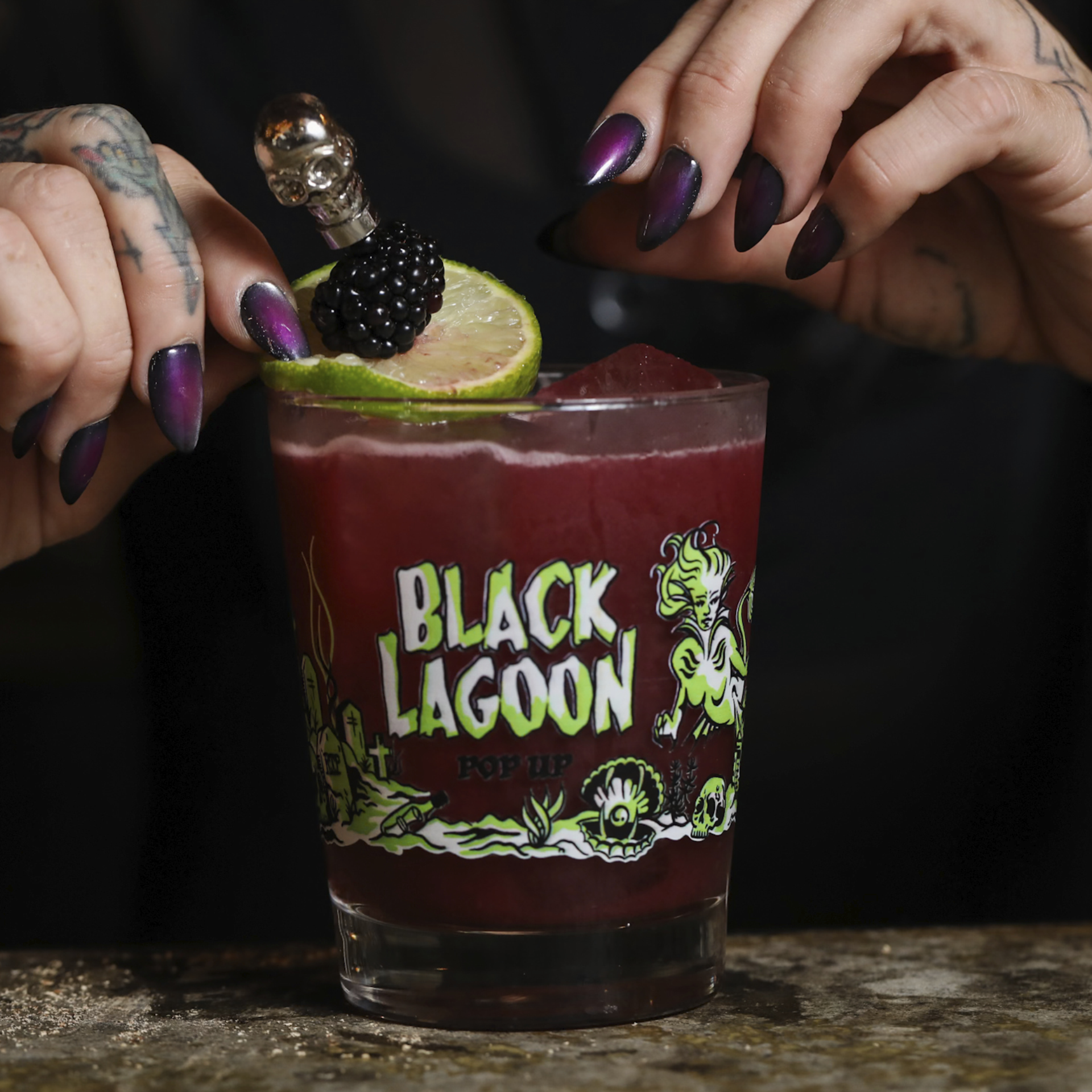Dark cocktail in Black Lagoon glass with skull‑topped garnish