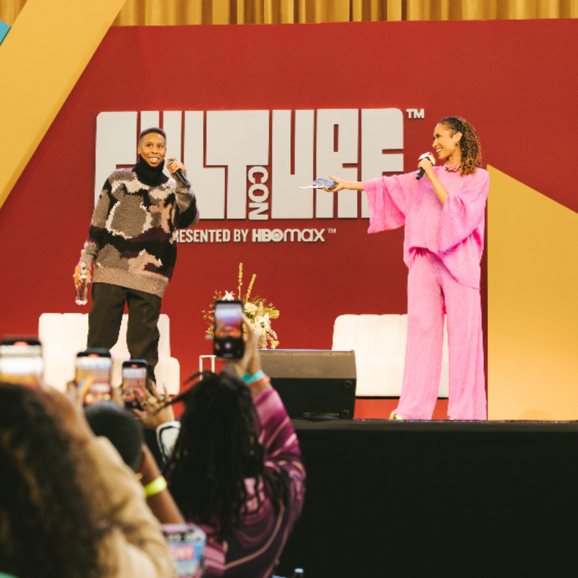 Two speakers on CultureCon stage with audience filming