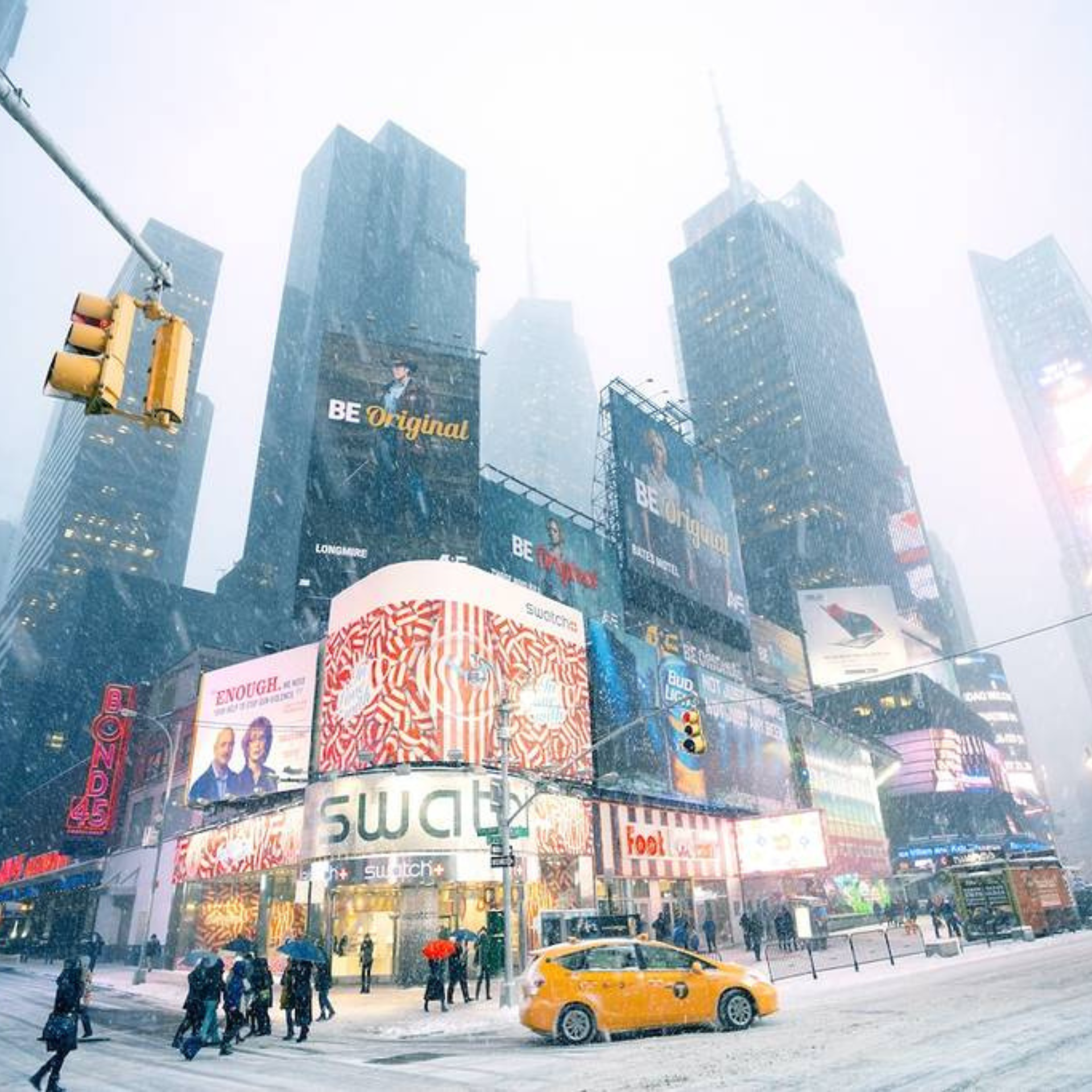 Snow blankets Times Square as a yellow cab drives past bundled-up pedestrians and glowing billboards
