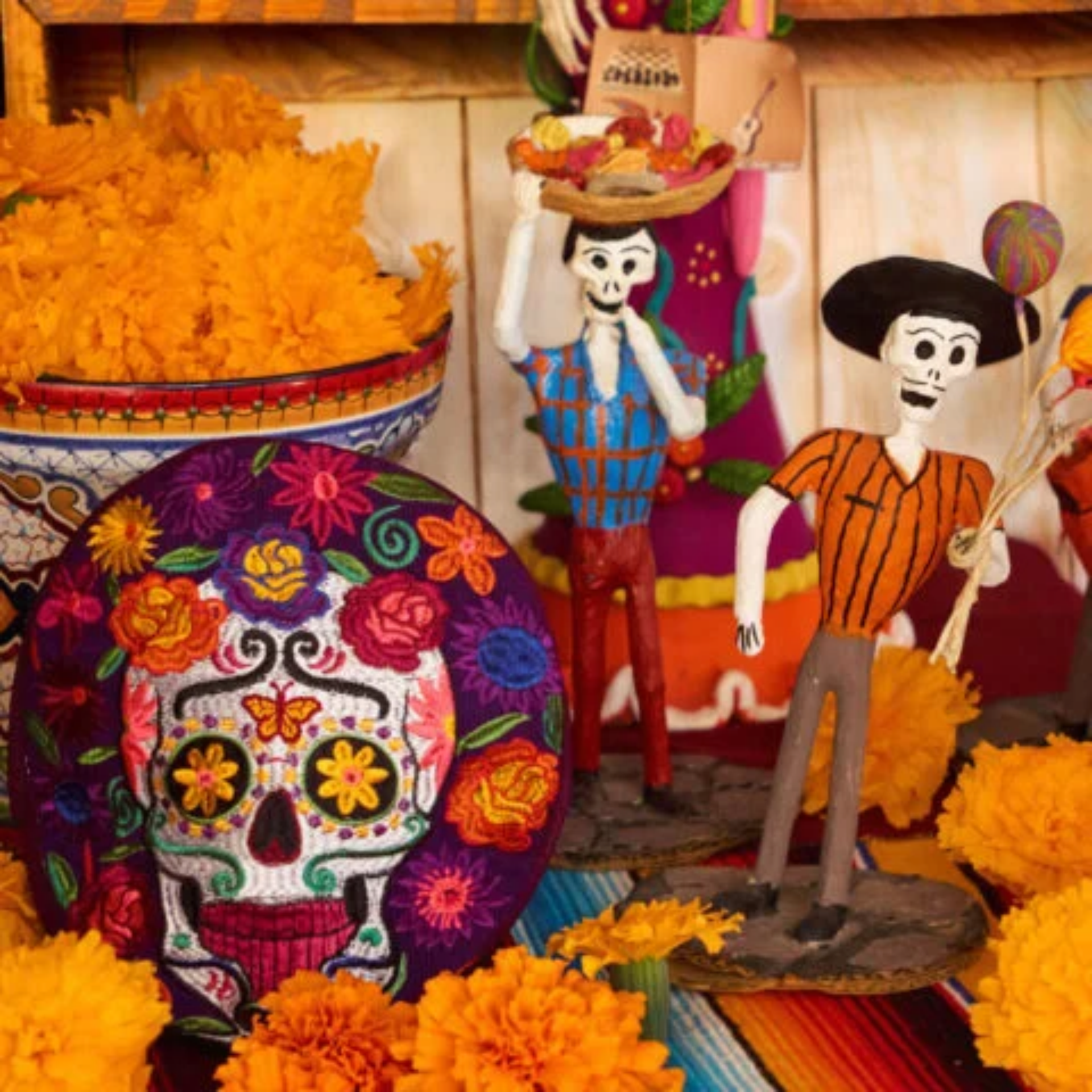 Day of the Dead altar with skeleton figurines, marigolds, and sugar skull embroidery
