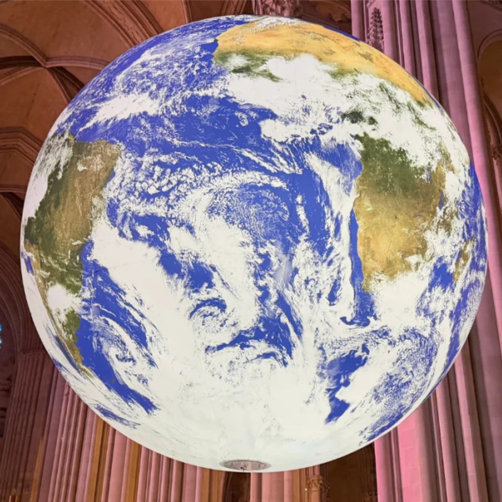 Large globe sculpture hanging in grand hall with columns