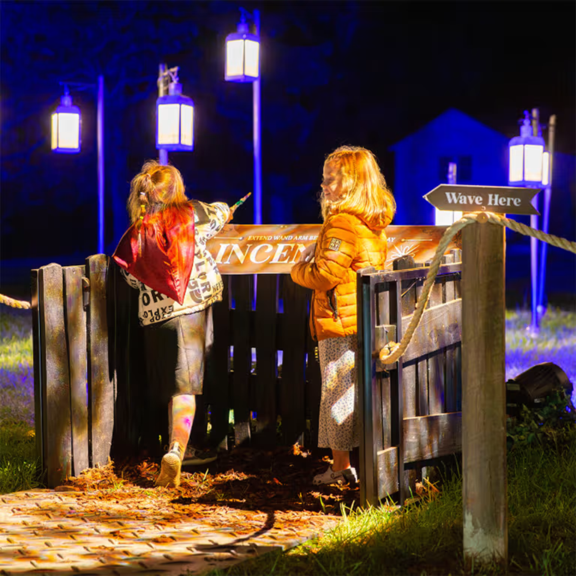 Children at night waving wands under lanterns and glowing signs
