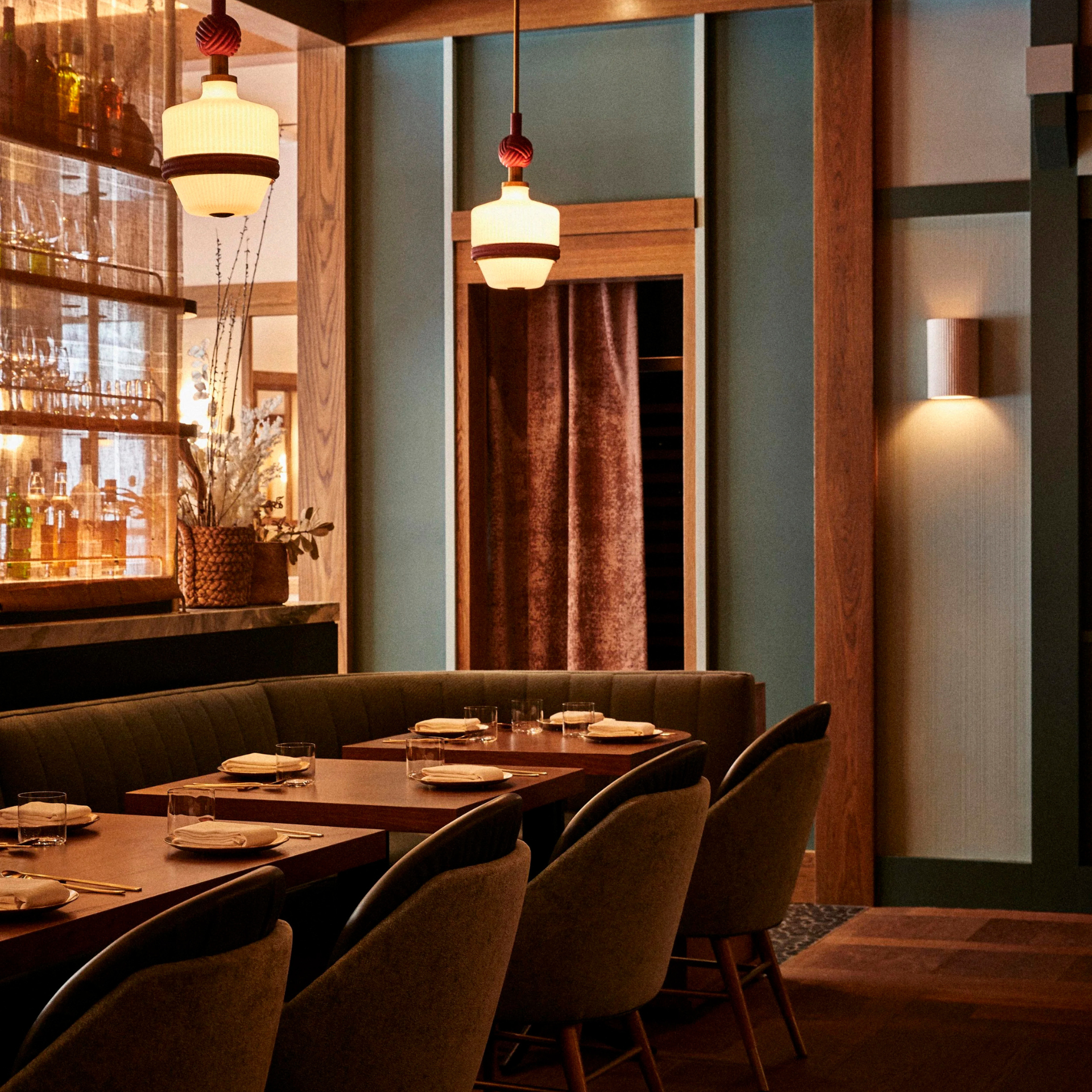 Elegant restaurant interior with a long set table, retro pendant lights, and warm, modern decor