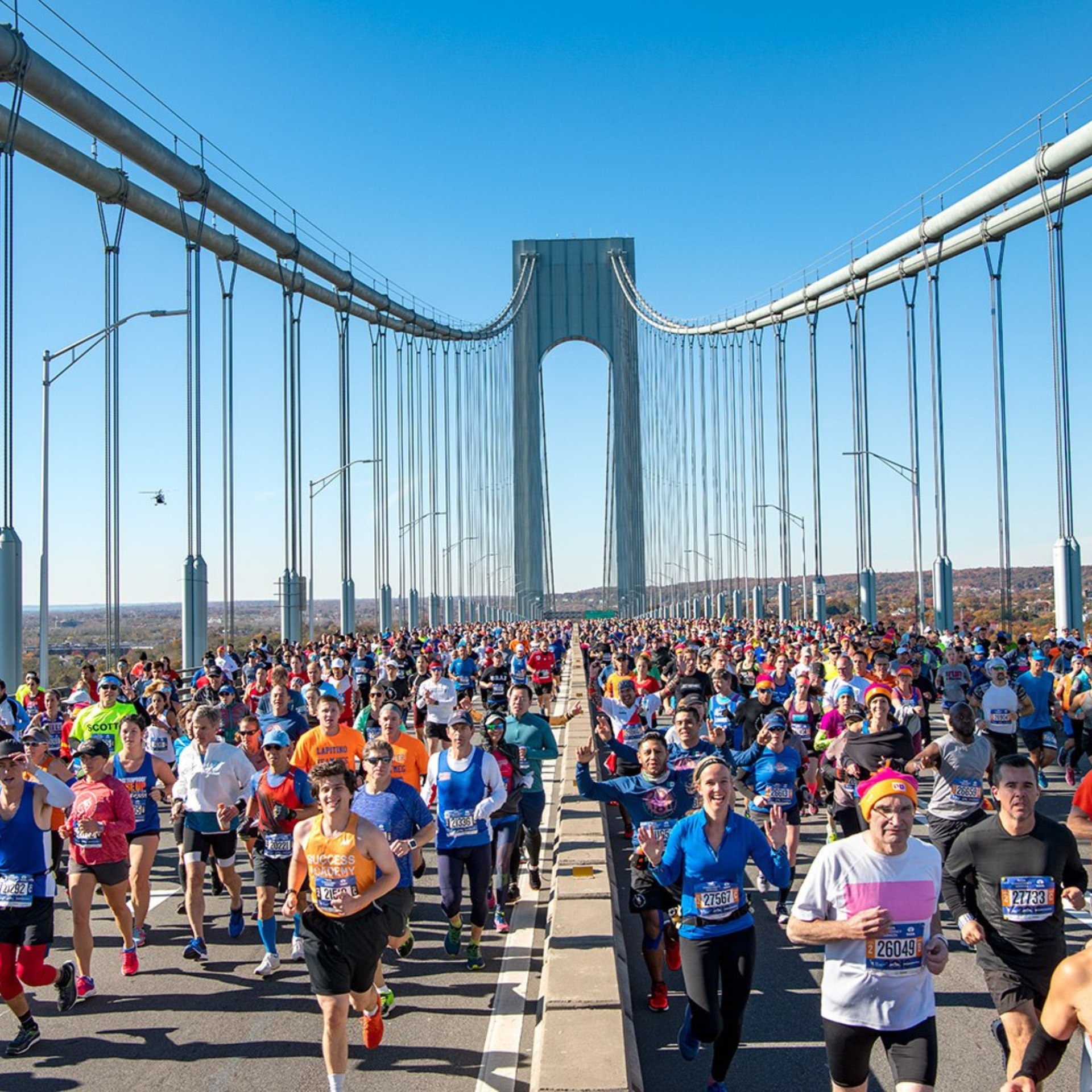 Thousands of marathon runners cross the Verrazzano-Narrows Bridge under a clear blue sky, kicking off a major race in New York City