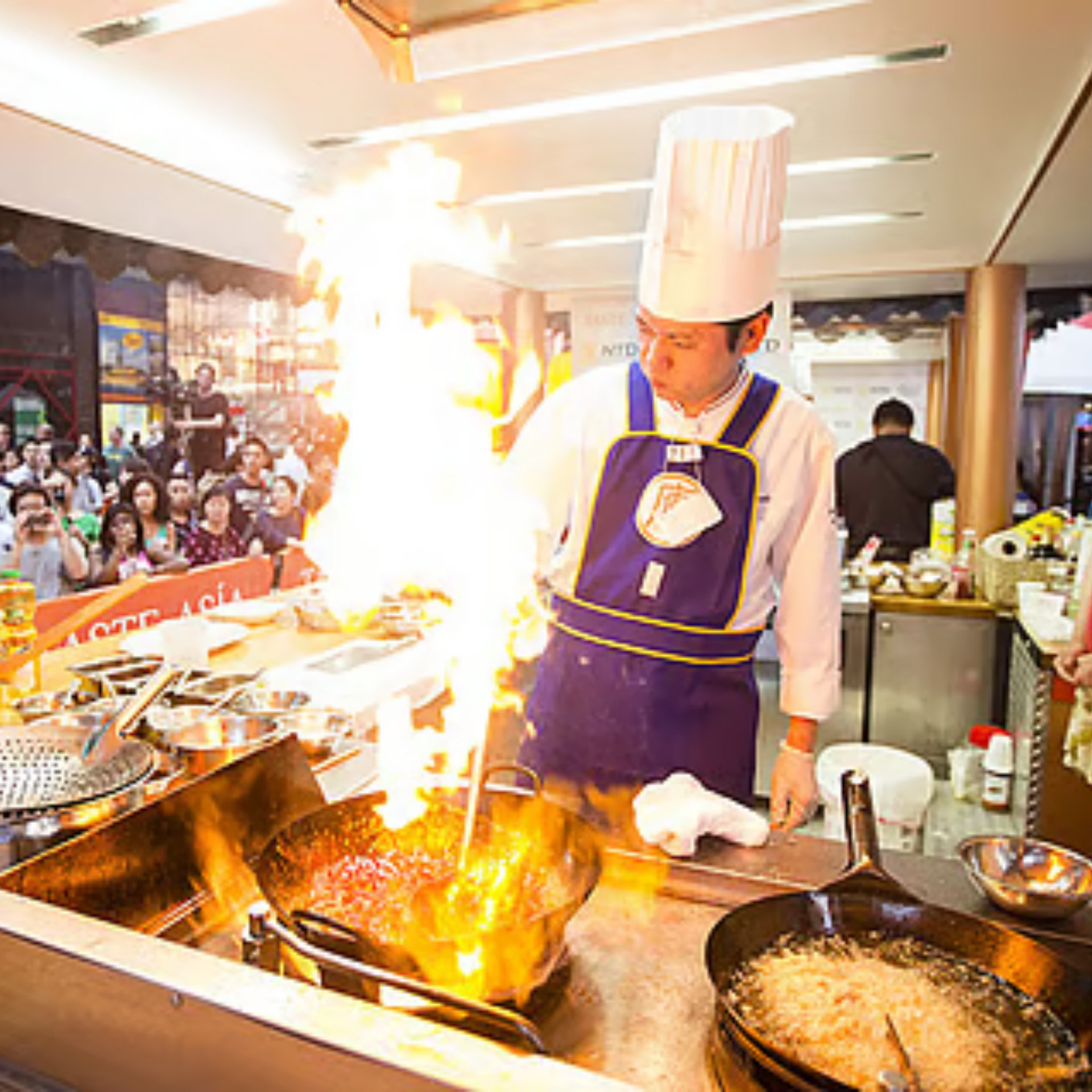 Chef stir‑fries in flaming wok at culinary event