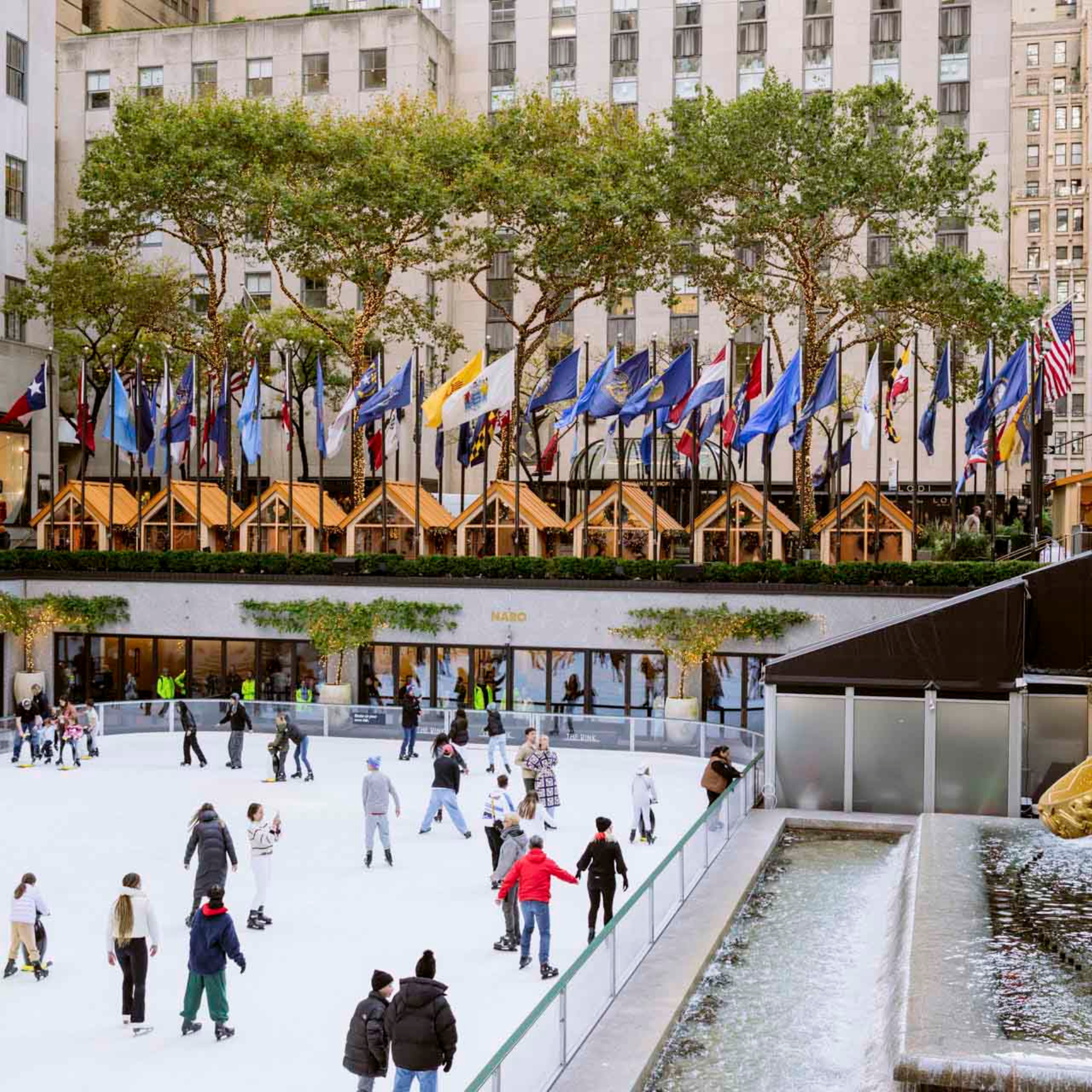 Skaters enjoy the rink at Rockefeller Center, framed by festive cabins and city flags
