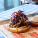 Pulled pork sandwich with slaw and sauce being added