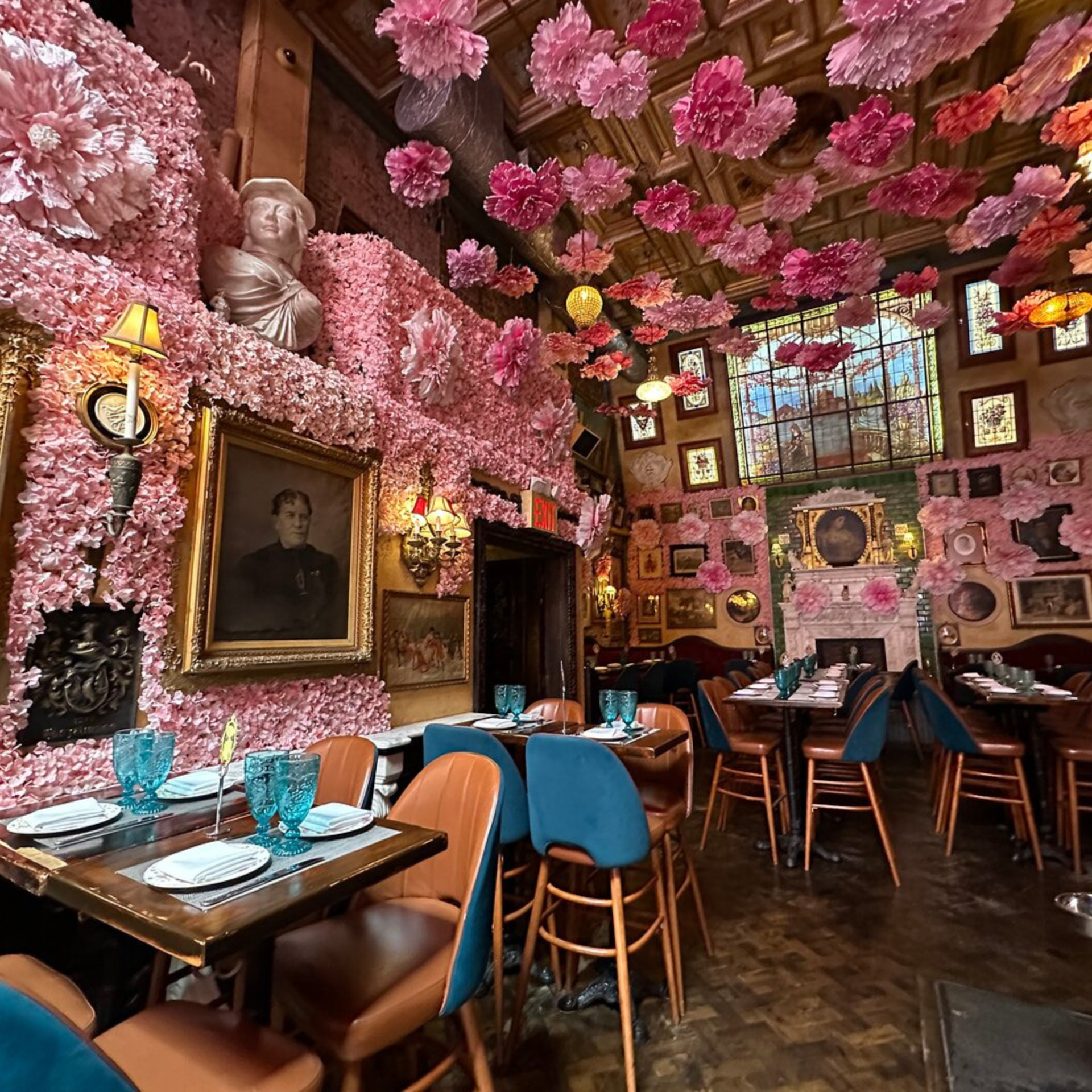 Whimsical dining room filled with pink flowers, eclectic art, and ornate furniture