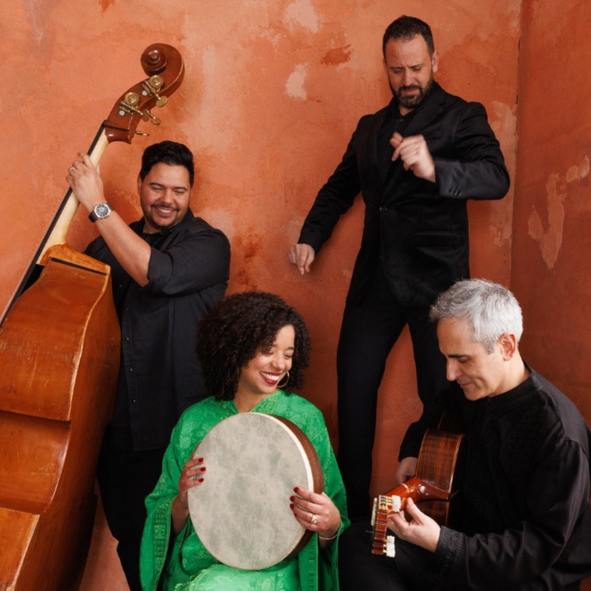 Four musicians performing in a cozy room, featuring drums, guitar, and double bass in a lively setting