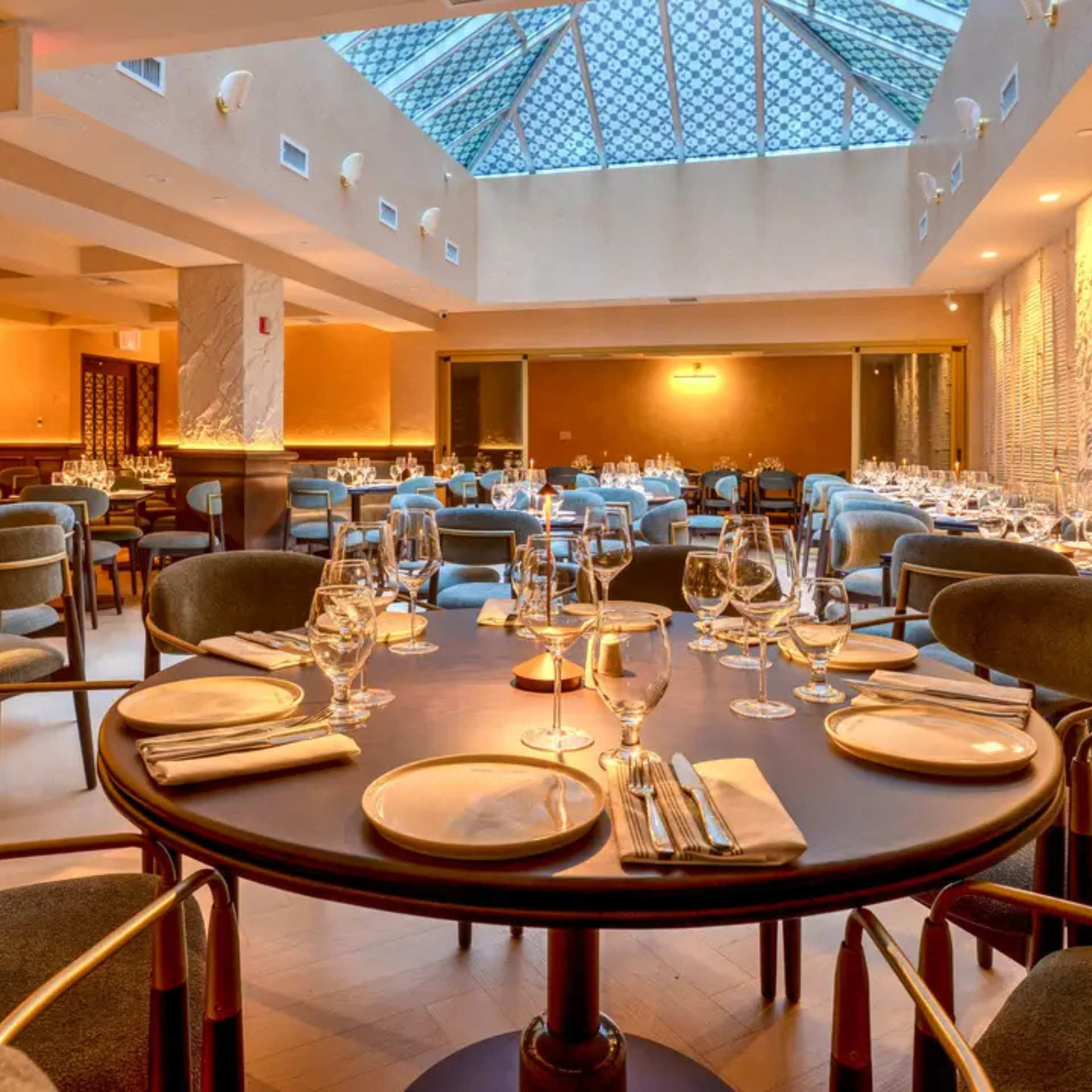 Elegant dining room with round tables, modern chairs, and a skylight ceiling
