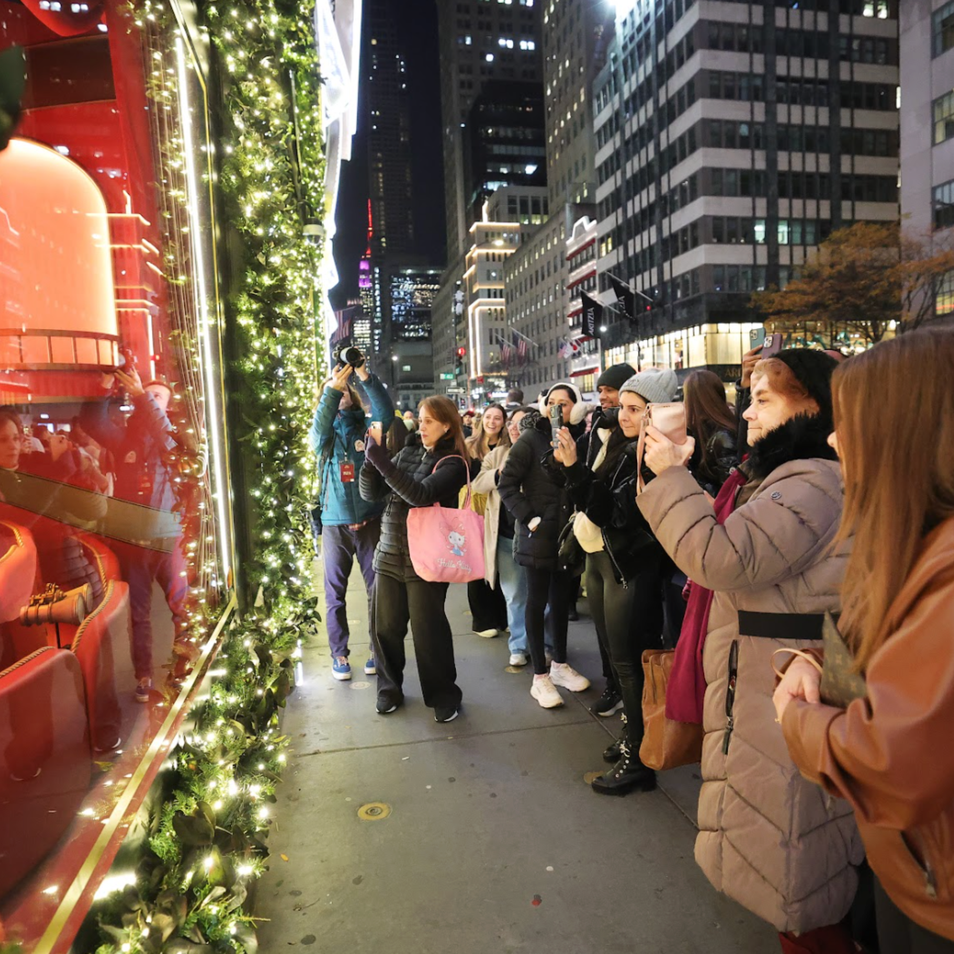A Group of people taking picture of Christmas lights in the building at night