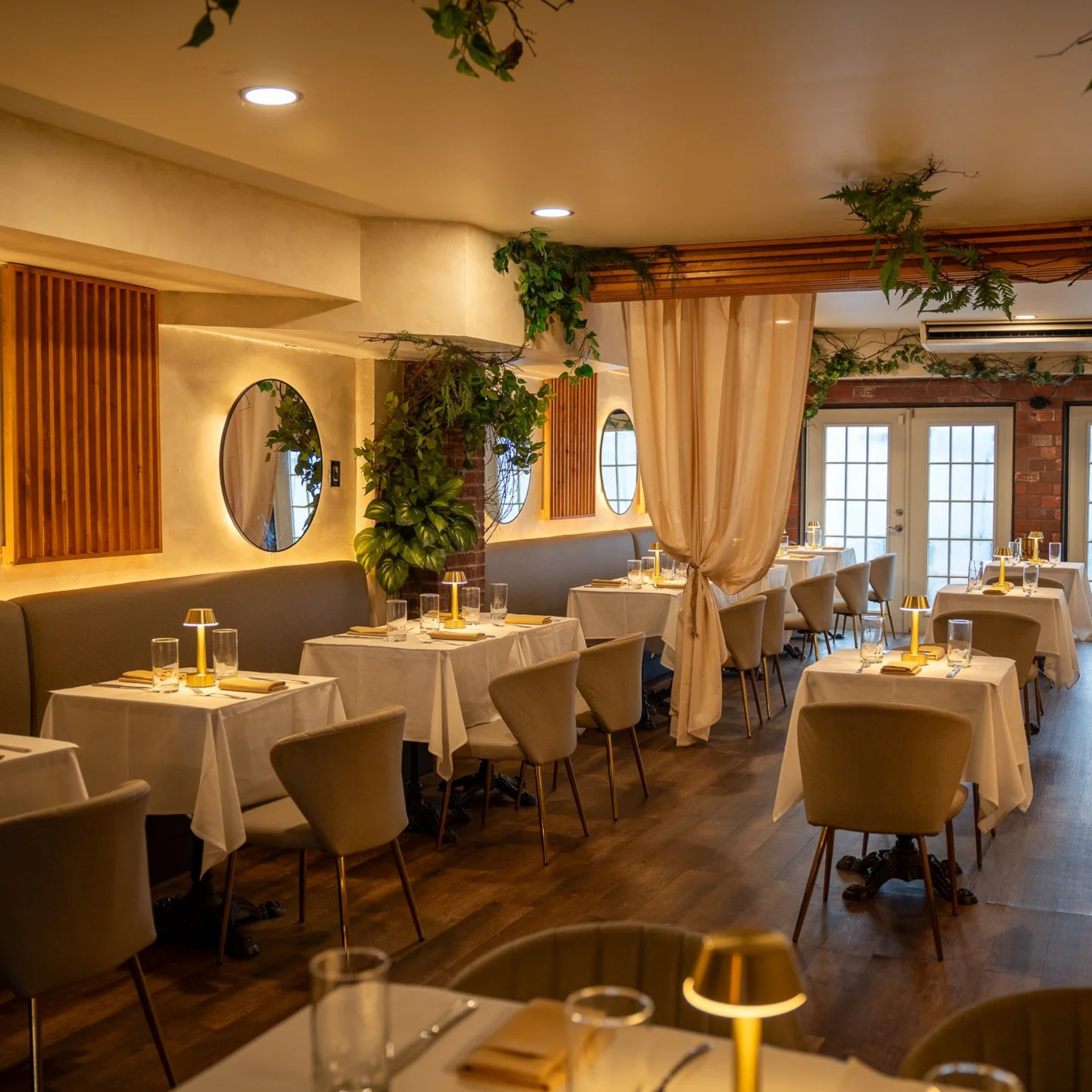 Modern restaurant interior with white tablecloths, warm lighting, and elegant neutral-toned decor